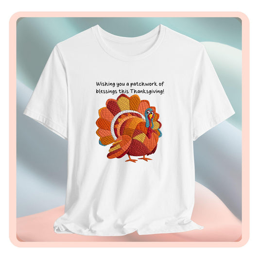 A thanksgiving quilting t-shirt featuring a quilted patchwork turkey in autumn colors with text "Wishing you a patchwork of blessings this Thanksgiving!" Turkey features various quilt patterns and textures in shades of orange, red, yellow, and blue. Whimsical, crafty holiday design perfect for quilting enthusiasts.