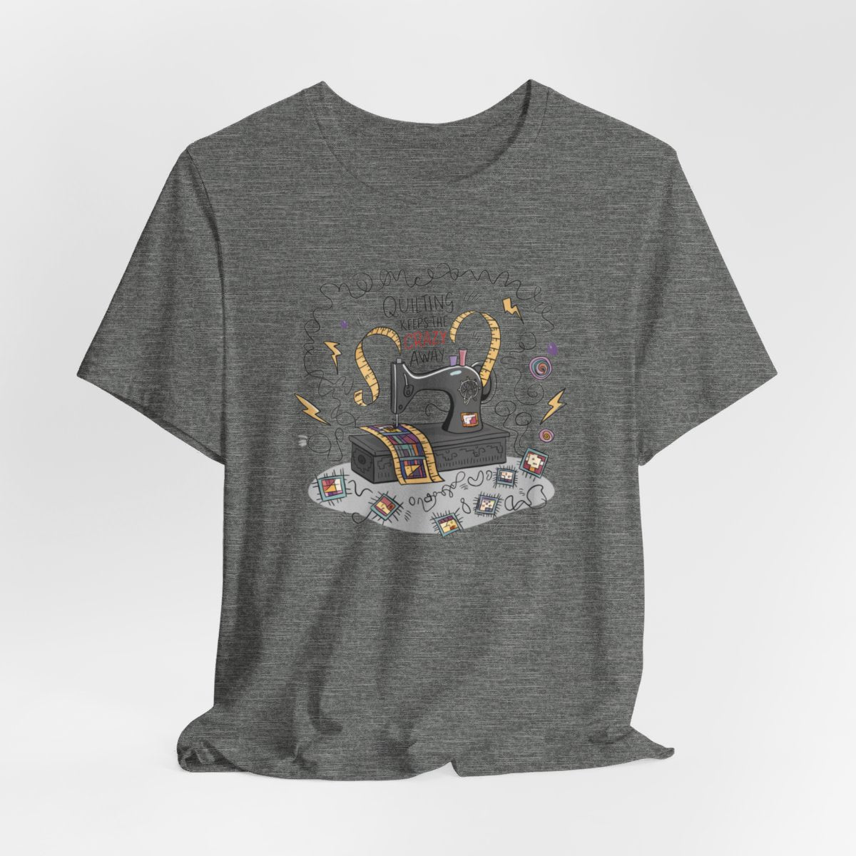 A Deep Heather T-Shirt with a vintage sewing machine, measuring tape heart, and text "Quilting Keeps the Crazy Away" amidst swirls and quilting motifs.