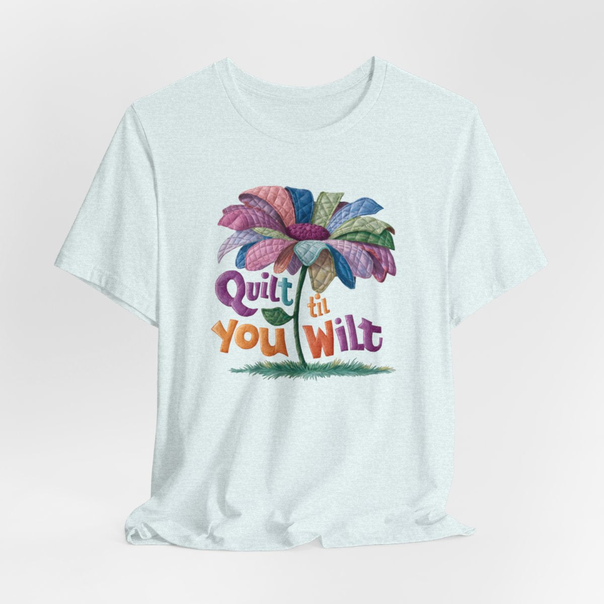 A Heather Ice Blue funny quilting T-Shirt with the phrase Quilt 'Till You Wilt showing a cheerful, but slightly wilted quilted flower design