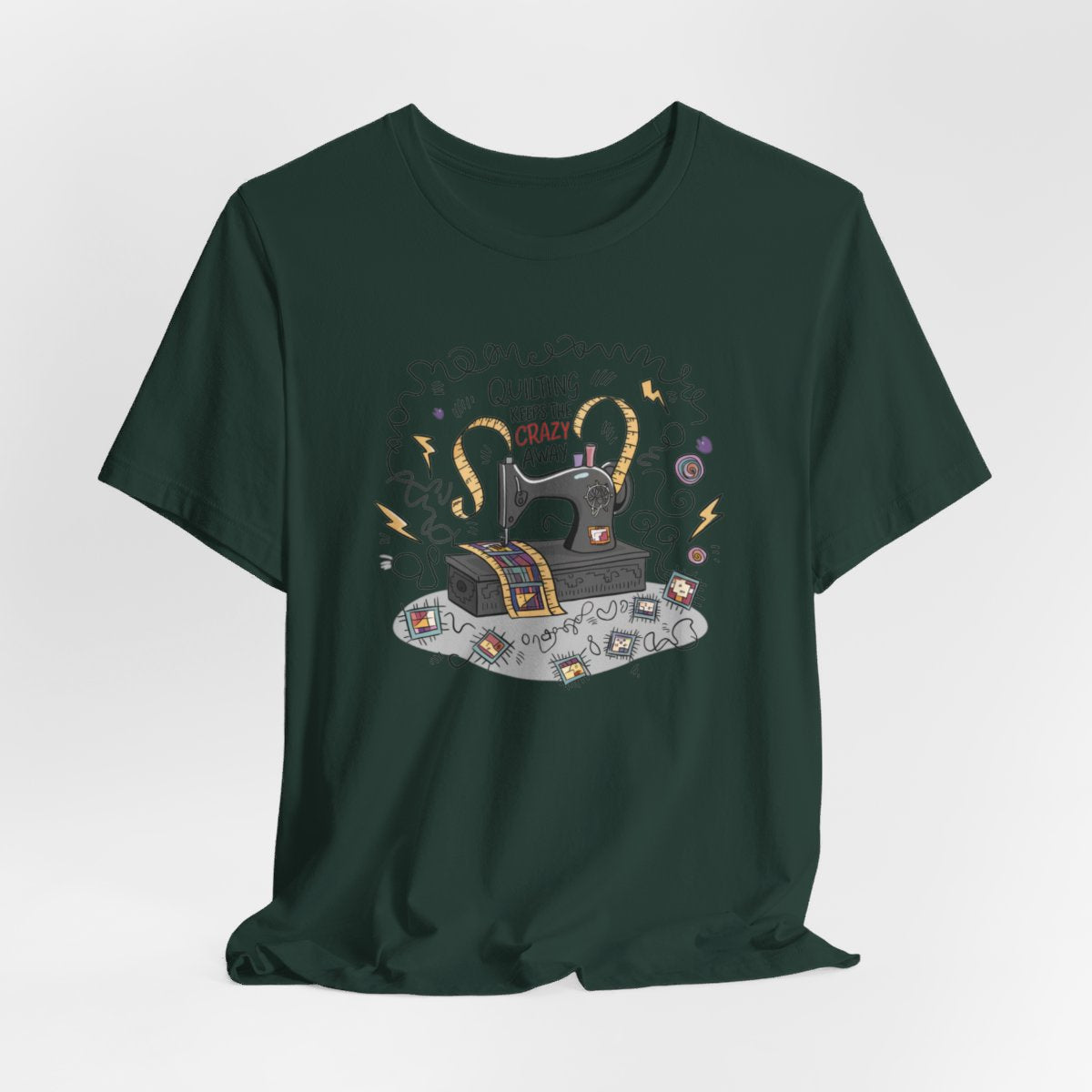 A Forest T-Shirt with a vintage sewing machine, measuring tape heart, and text "Quilting Keeps the Crazy Away" amidst swirls and quilting motifs.