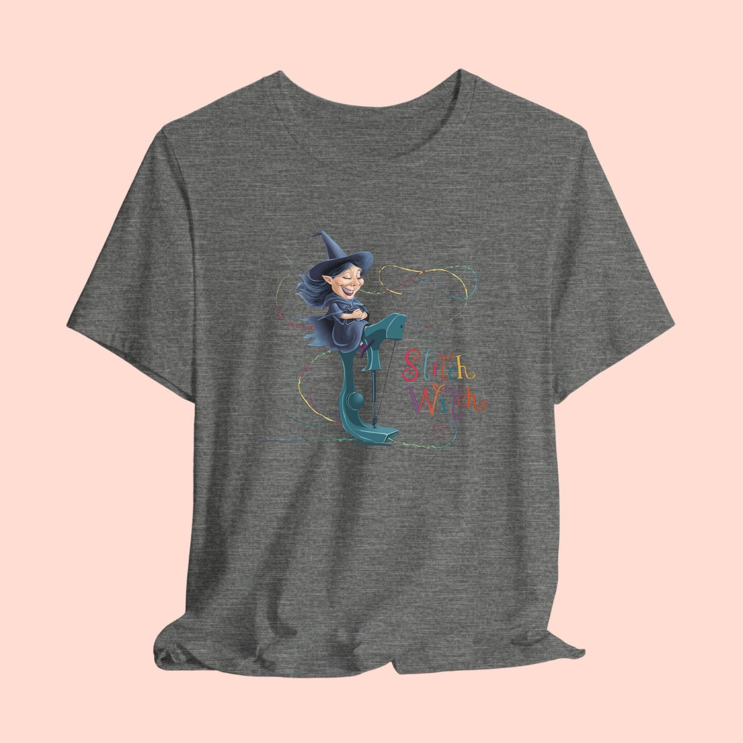 A T-shirt with a cartoon illustration of a smiling witch with pointed hat riding a teal sewing machine. Colorful stitches swirl around her in the air. Text reads "Stitch Witch" in playful, multicolored letters.