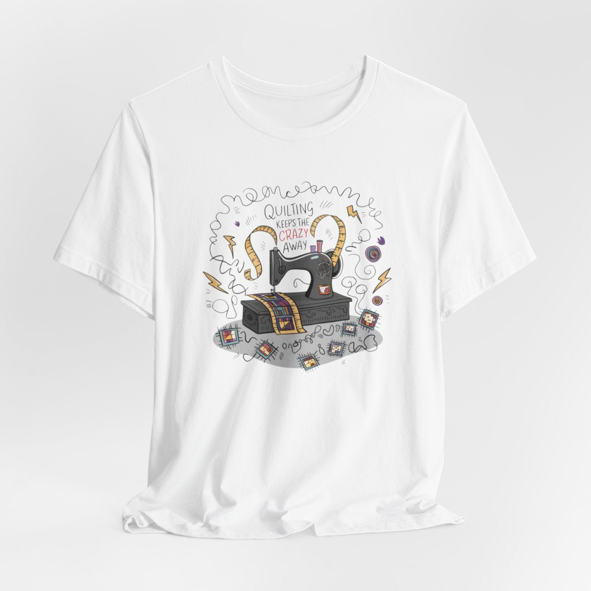 A White T-Shirt with a vintage sewing machine, measuring tape heart, and text "Quilting Keeps the Crazy Away" amidst swirls and quilting motifs.