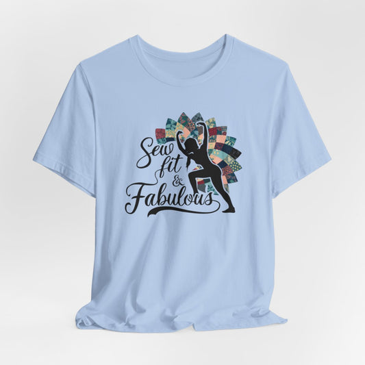 A Baby Blue T-Shirt featuring a black silhouette of woman with raised arms against colorful patchwork background. Text reads "Sew fit & Fabulous" in stylized script.