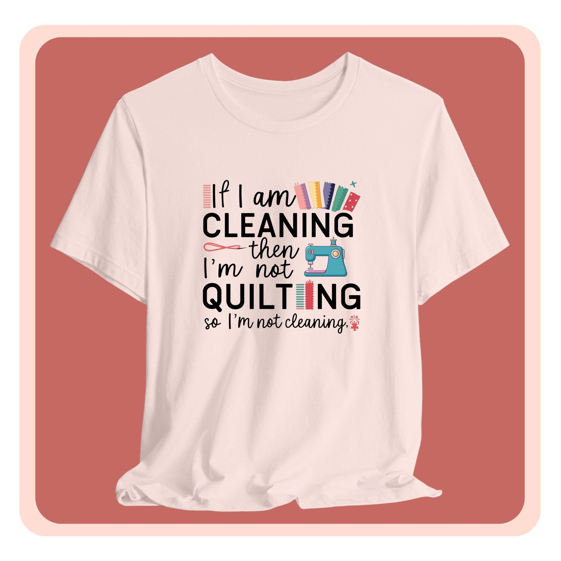 A funny quilting T-Shirt with the phrase If I am Cleaning then I'm not Quilting in a bold and cheerful font with images of quilting icons and supplies