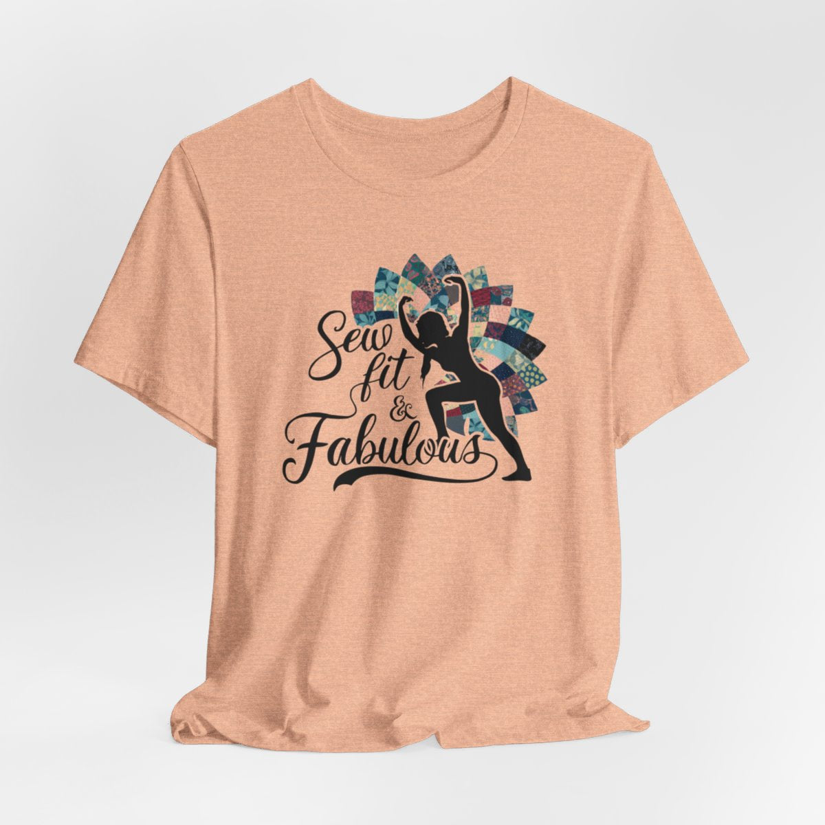 A Heather Peach T-Shirt featuring a black silhouette of woman with raised arms against colorful patchwork background. Text reads "Sew fit & Fabulous" in stylized script.
