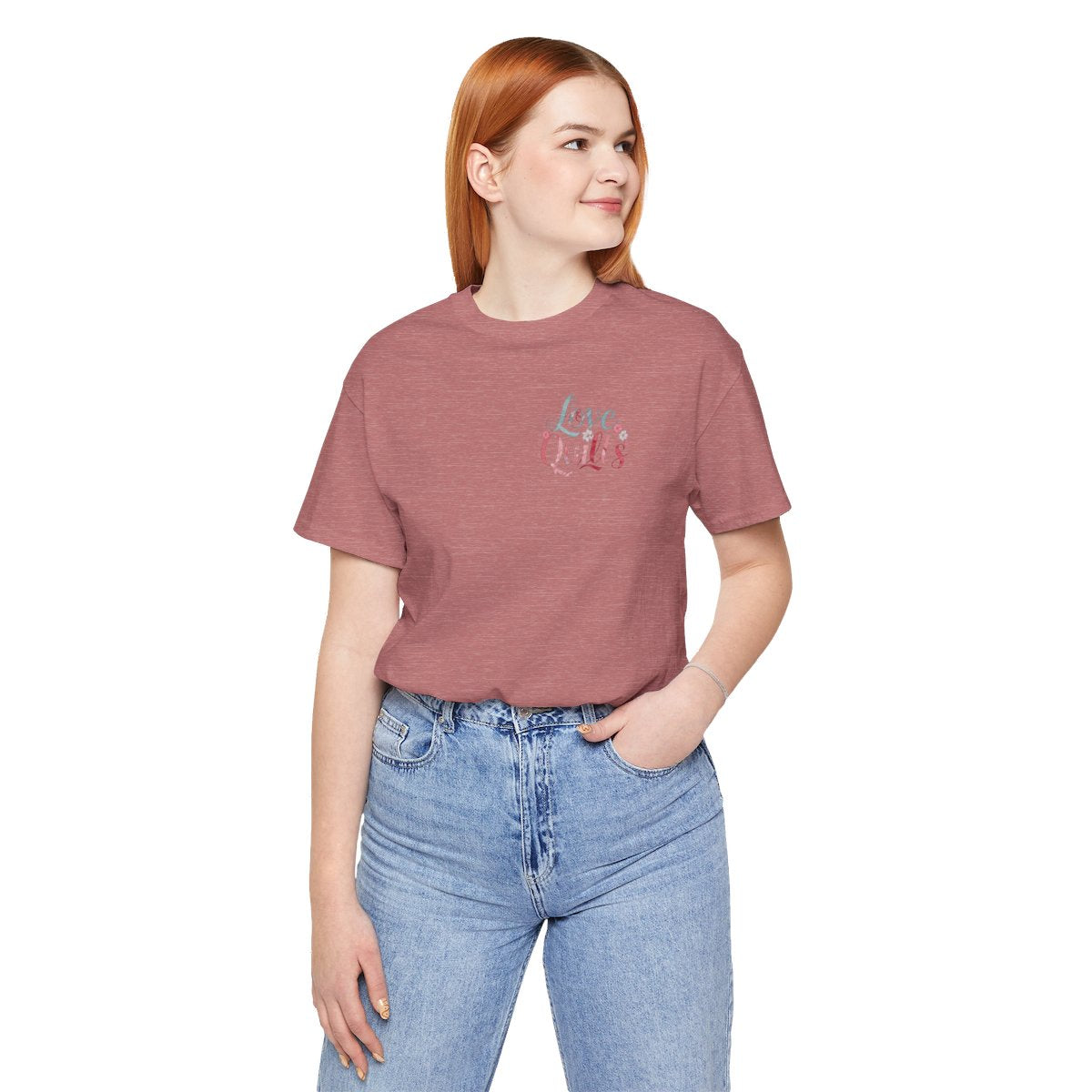 A Heather Mauve t-shirt spelling out "Love Quilts". The word "Love" is in teal, while "Quilts" features various shades of pink and red. Small flowers in white and pink adorn the letters, creating a floral and quilting-inspired artwork.