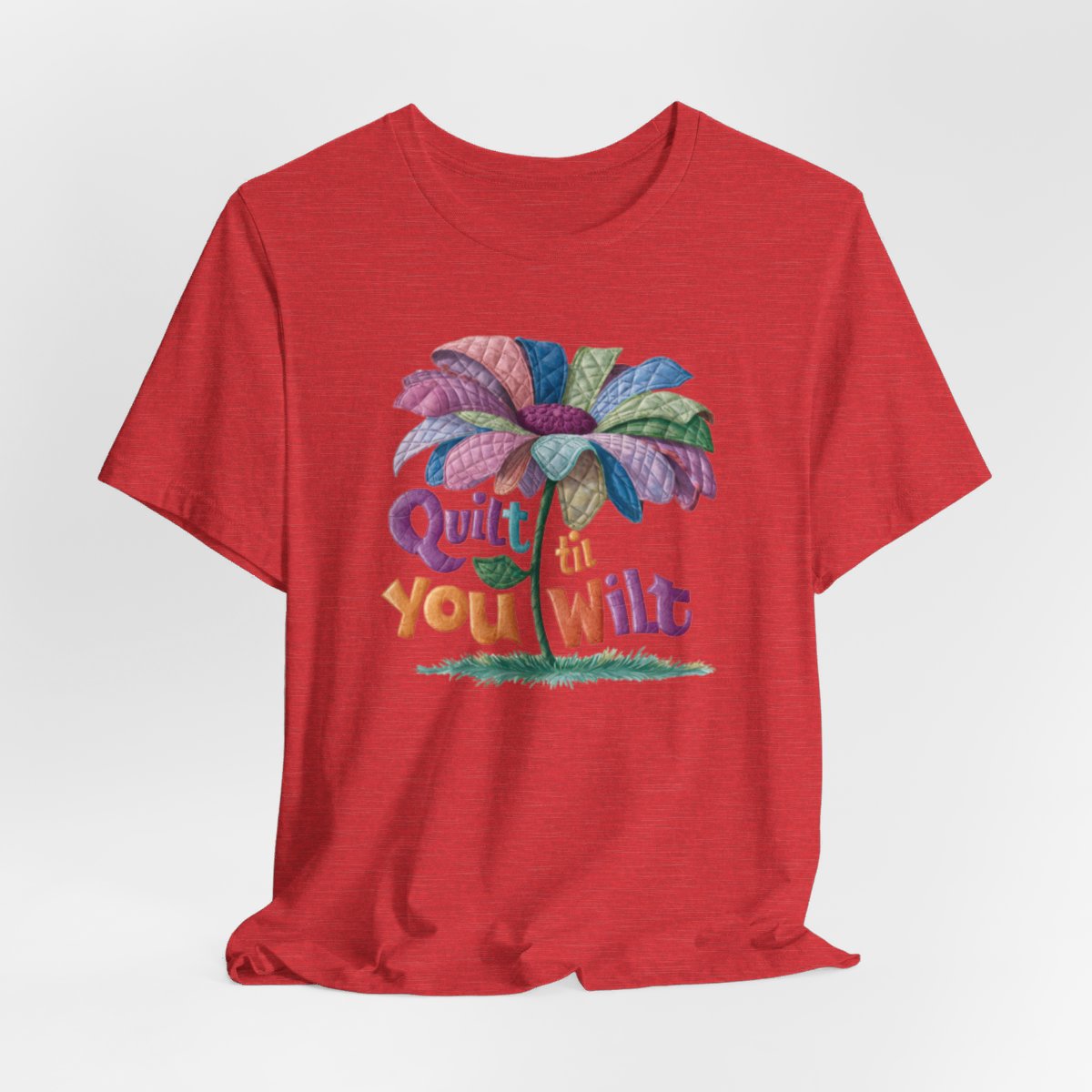 A Heather Red funny quilting T-Shirt with the phrase Quilt 'Till You Wilt showing a cheerful, but slightly wilted quilted flower design