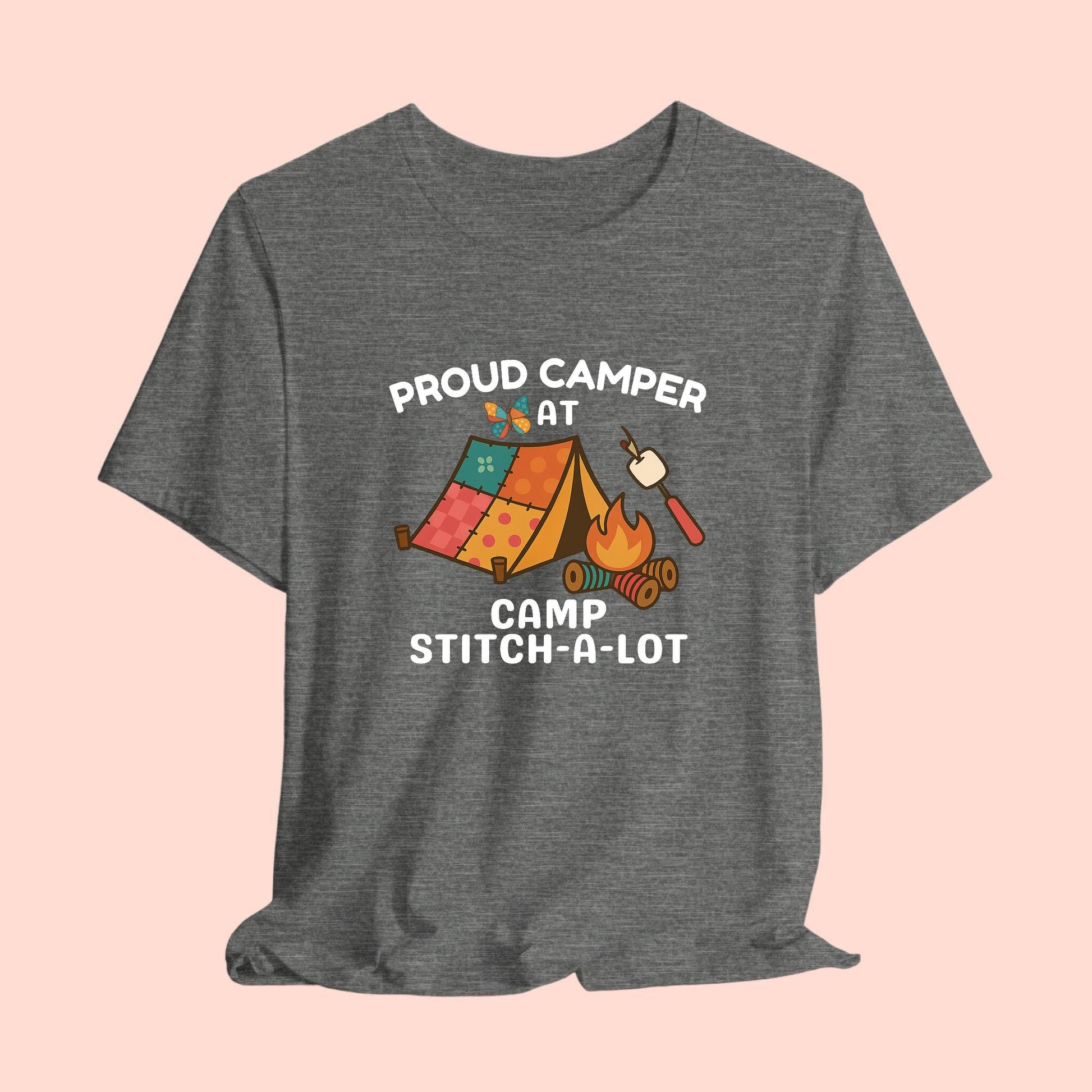 A A t-shirt featuring a colorful design with a patchwork tent, thread spool campfire, marshmallow on a seam ripper stick, and a butterfly. Text reads "Proud Camper at Camp Stitch-a-Lot." Fun gift for quilting retreats.