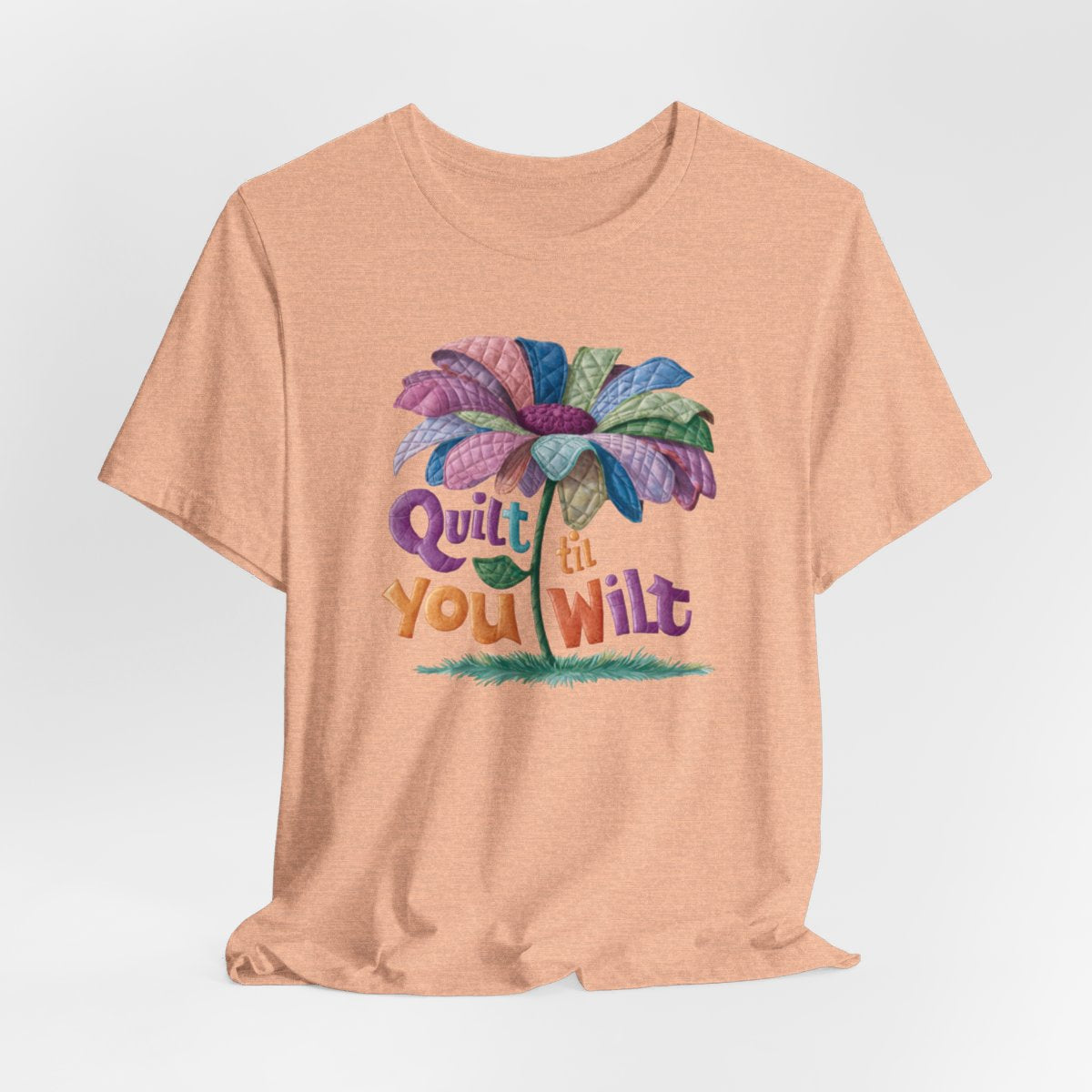 A Heather Peach funny quilting T-Shirt with the phrase Quilt 'Till You Wilt showing a cheerful, but slightly wilted quilted flower design