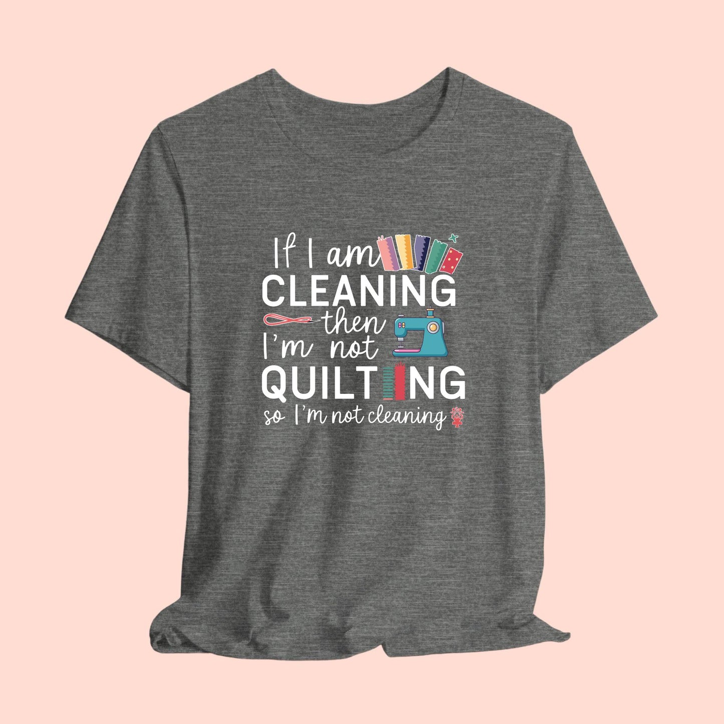 A funny quilting T-Shirt with the phrase If I am Cleaning then I'm not Quilting in a bold and cheerful font with images of quilting icons and supplies