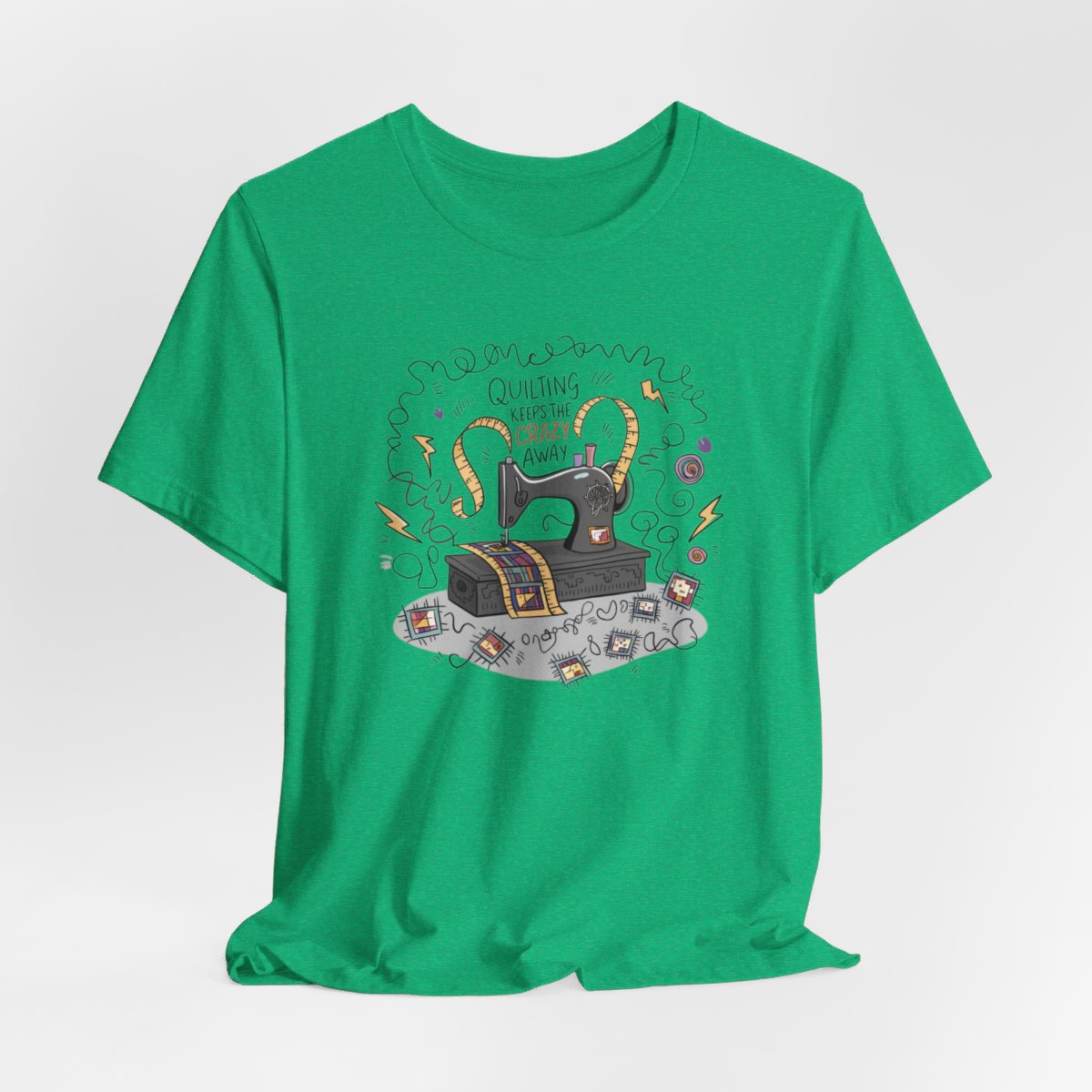 A Heather Kelly T-Shirt with a vintage sewing machine, measuring tape heart, and text "Quilting Keeps the Crazy Away" amidst swirls and quilting motifs.