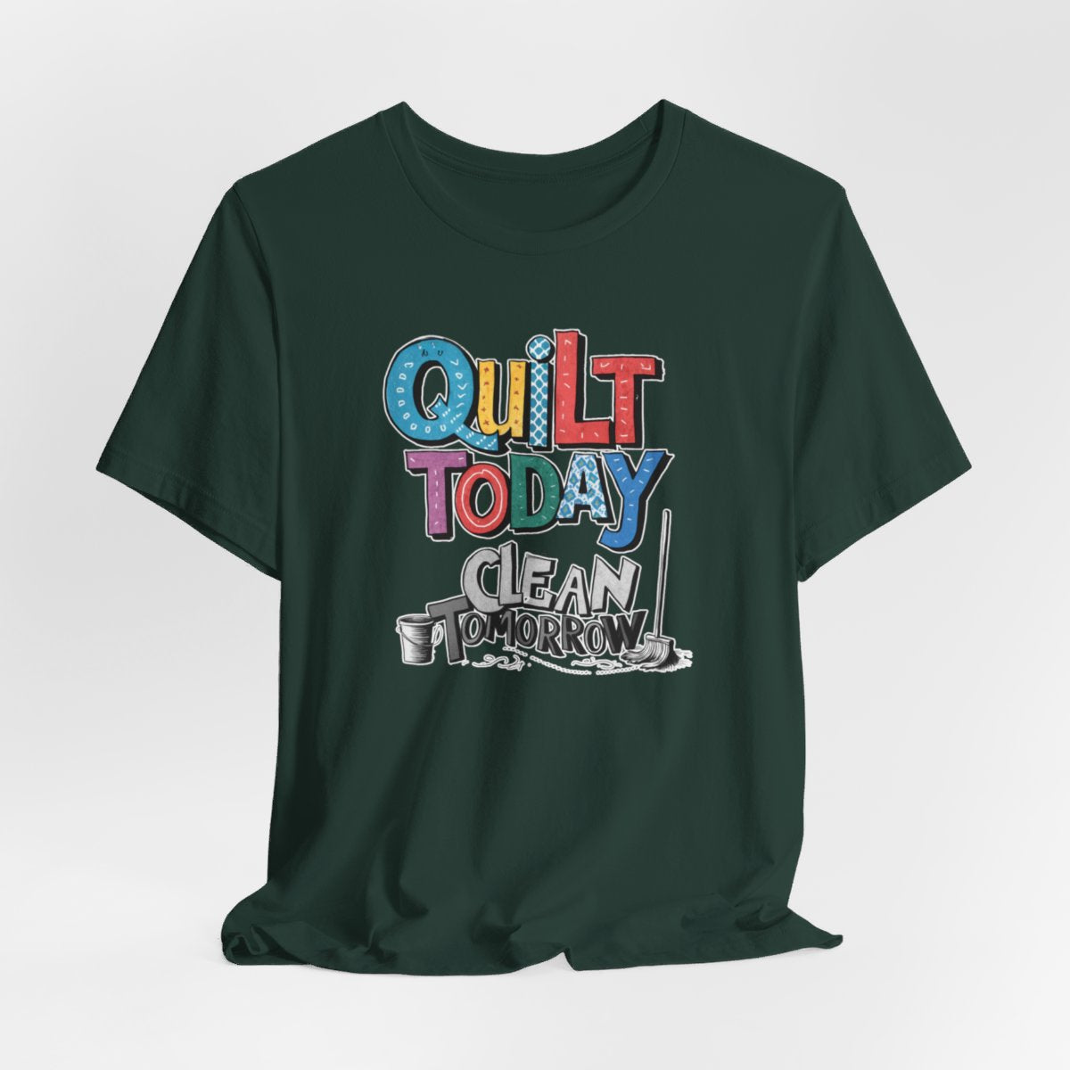 A Forest funny quilting T-Shirt with the phrase Quilt Today, Clean Tomorrow in a bold and cheerful font with a broom off to the side