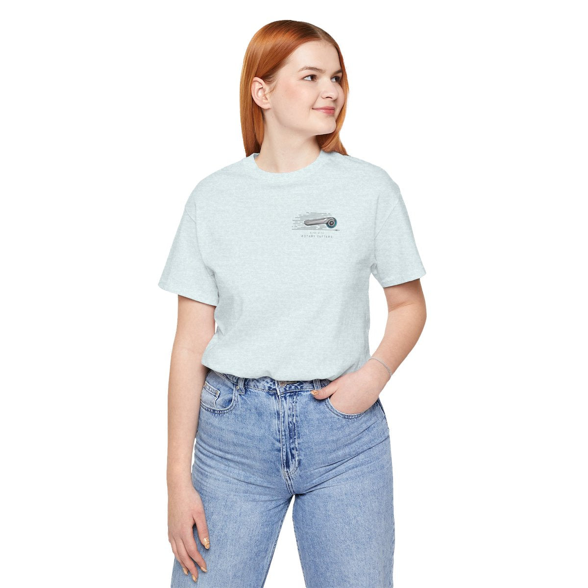 A Heather Ice Blue T-shirt featuring minimalist graphic of a sleek rotary cutter in motion with speed lines. Text below reads "RUNS WITH ROTARY CUTTERS" in a modern font.