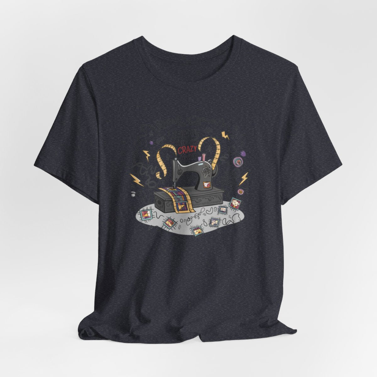 A Heather Navy T-Shirt with a vintage sewing machine, measuring tape heart, and text "Quilting Keeps the Crazy Away" amidst swirls and quilting motifs.