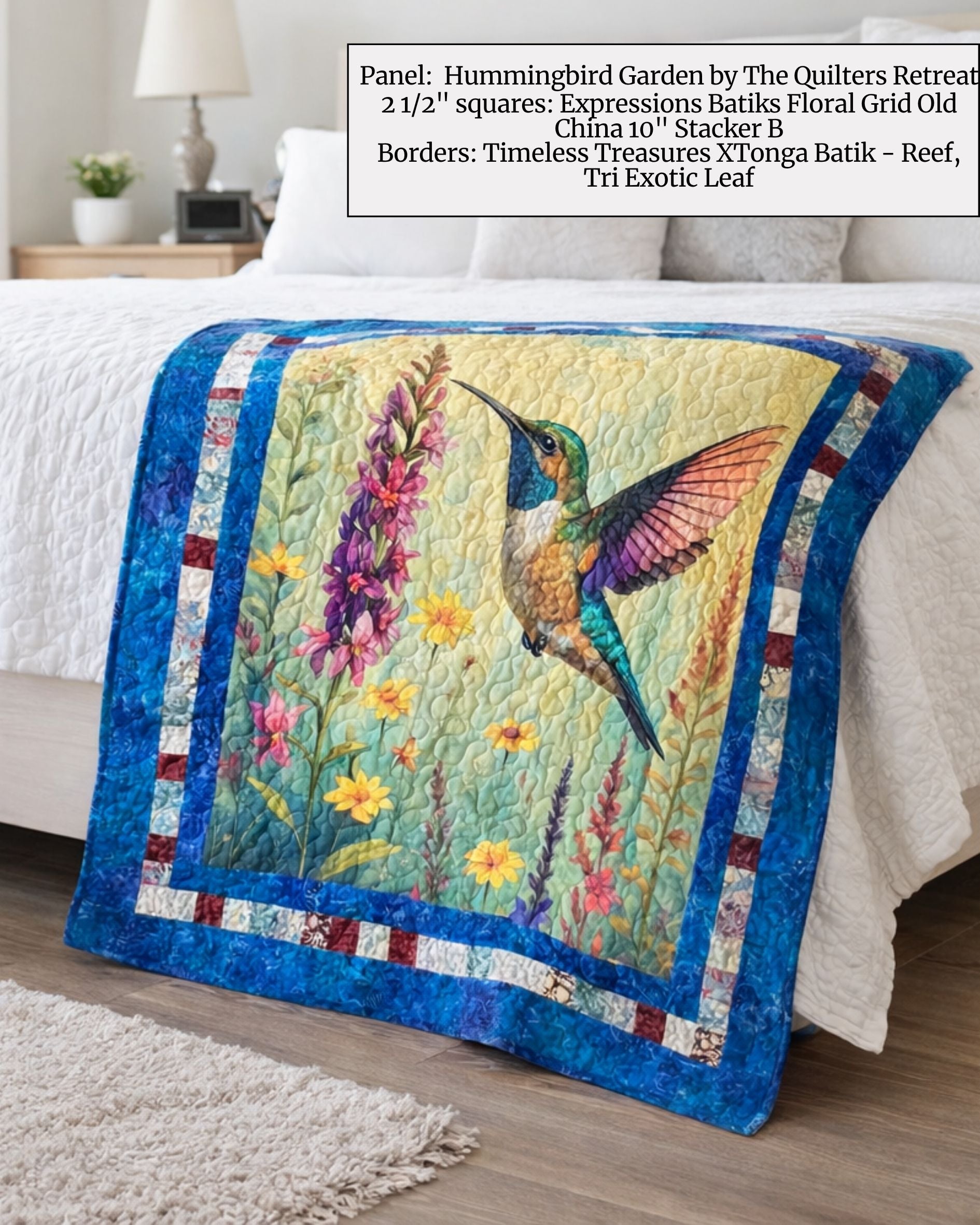 Hummingbird Garden quilt panel sewn into a blue-bordered quilt on a bed