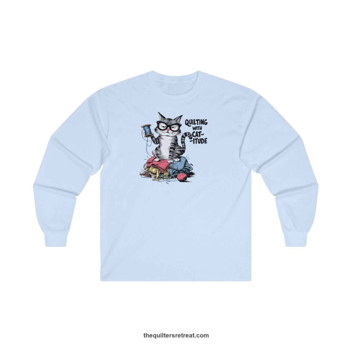 A Light Blue Long Sleeve T-Shirt with a grumpy cat holding thread spool atop fabric pile with "Quilting with Cat-itude" text