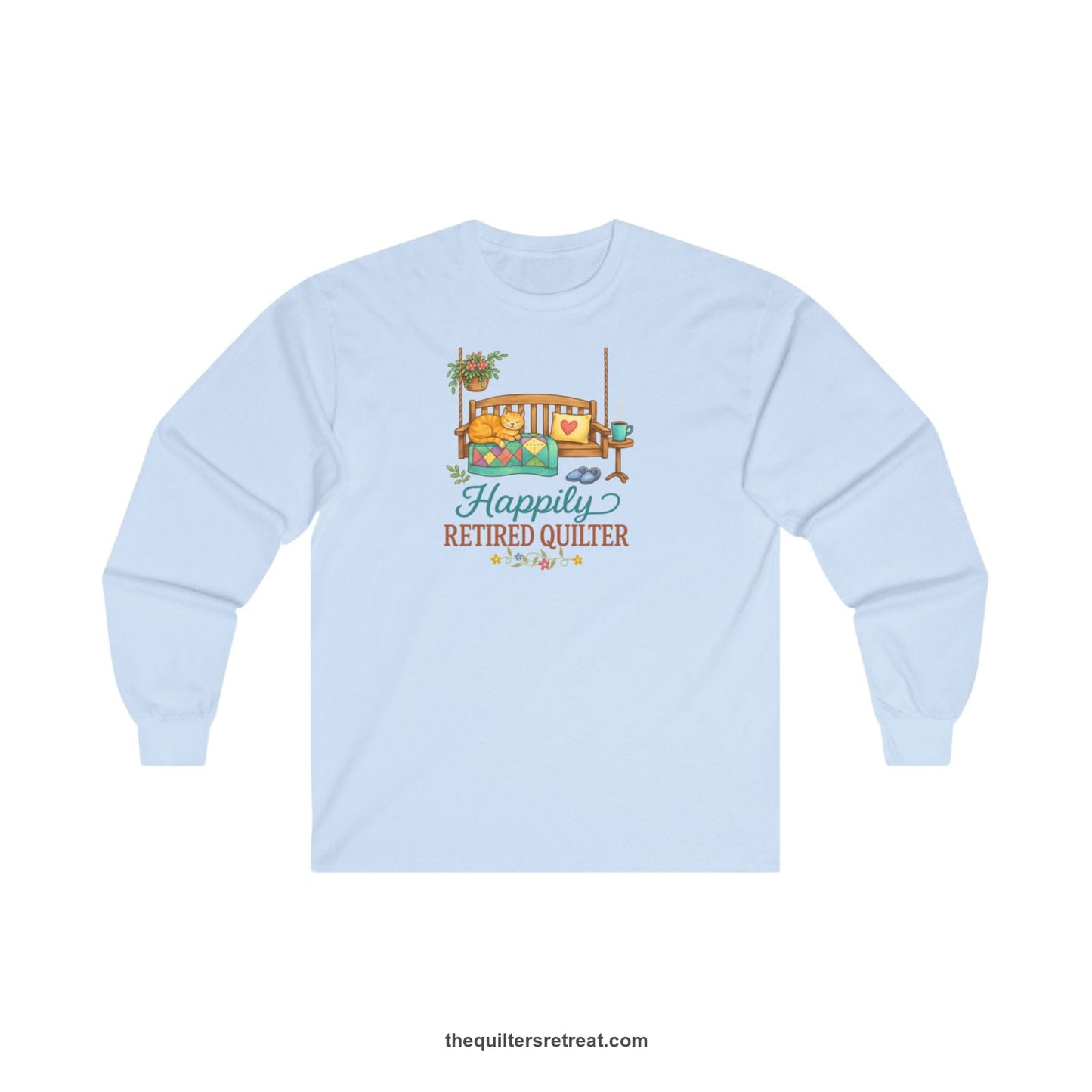 A Light Blue Long Sleeve T-Shirt with a hanging bench with cozy cat and quilt, surrounded by plants, "Happily Retired Quilter" text