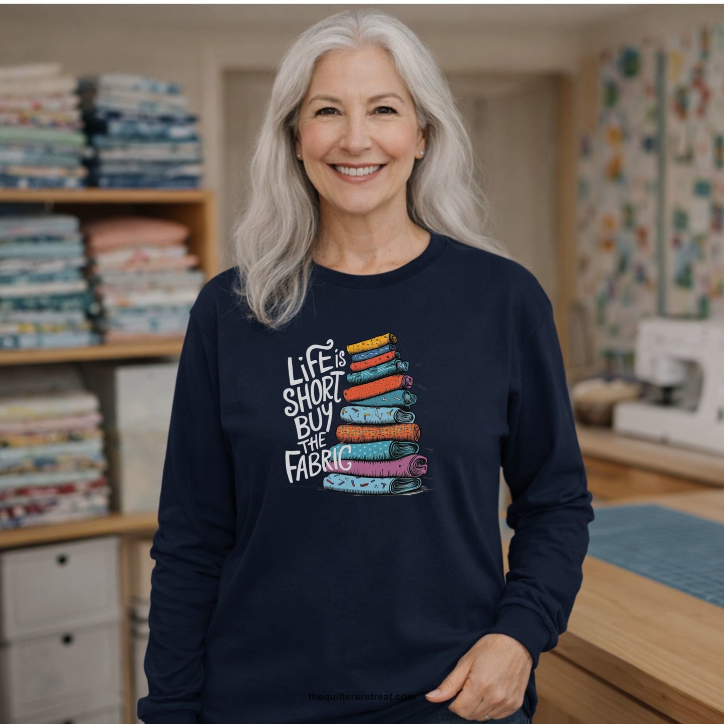 A Long Sleeve T-Shirt with a illustration of colorful fabric rolls with bold "Life is Short Buy the Fabric" text