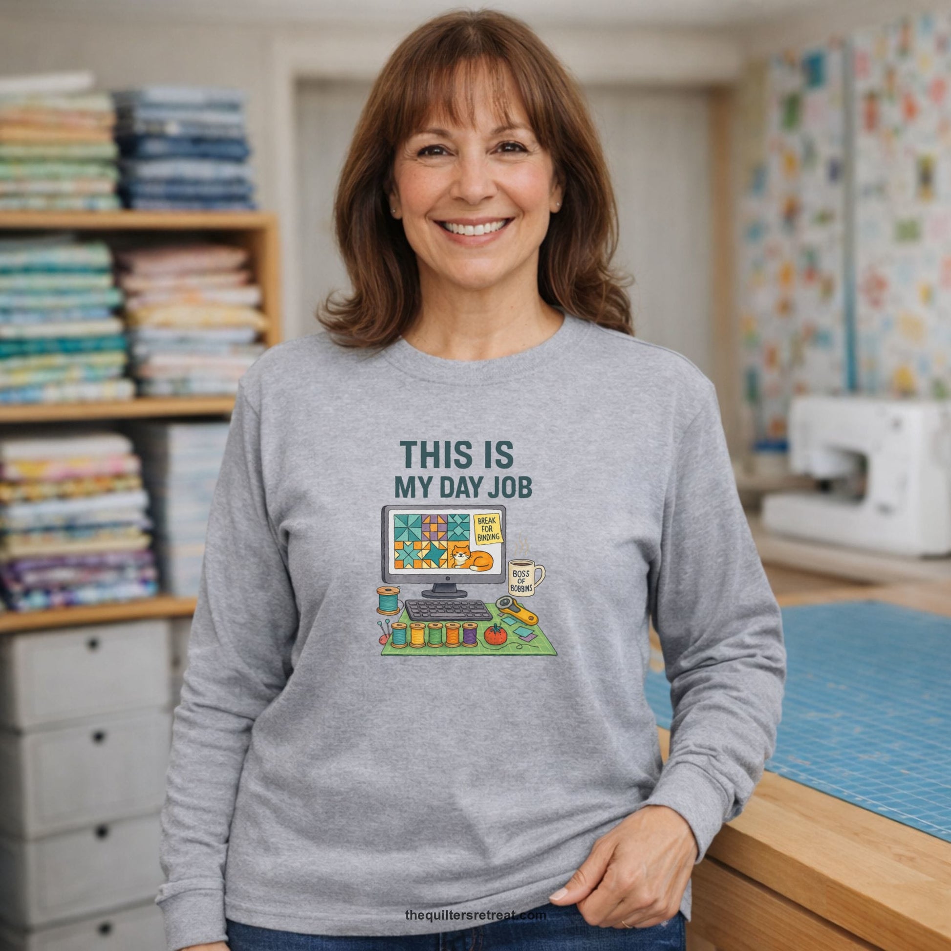 A Long Sleeve T-Shirt with a computer quilt design, cat illustration, "THIS IS MY DAY JOB" text with sewing tools, playful style