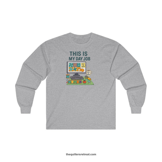 A Long Sleeve T-Shirt with a computer quilt design, cat illustration, "THIS IS MY DAY JOB" text with sewing tools, playful style