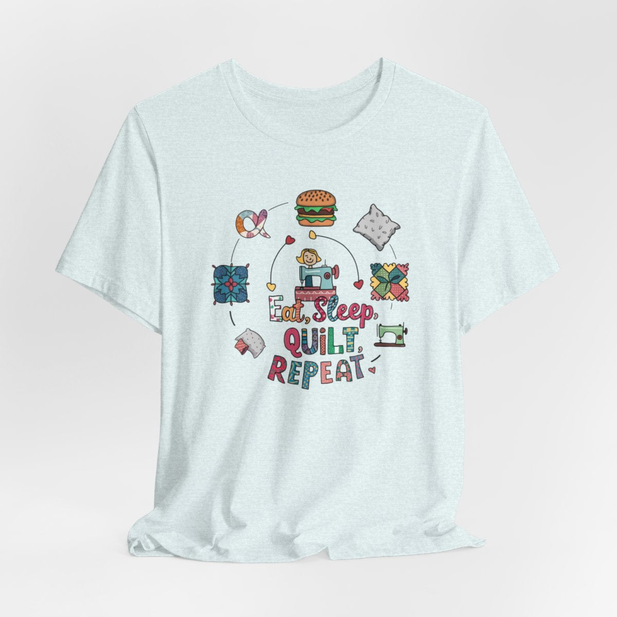 A Heather Ice Blue funny quilting T-Shirt with the phrase Eat, Sleep, Quilt, Repeat  showing the cycle of a quilter's day with eating, sleeping, and quilting