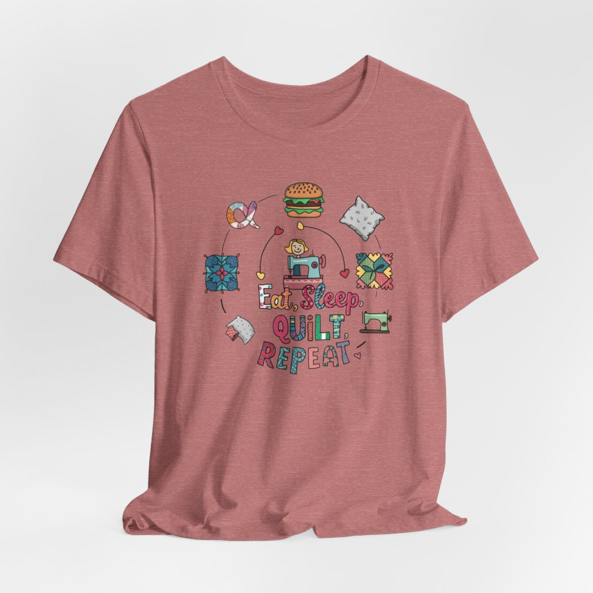 A Heather Mauve funny quilting T-Shirt with the phrase Eat, Sleep, Quilt, Repeat  showing the cycle of a quilter's day with eating, sleeping, and quilting