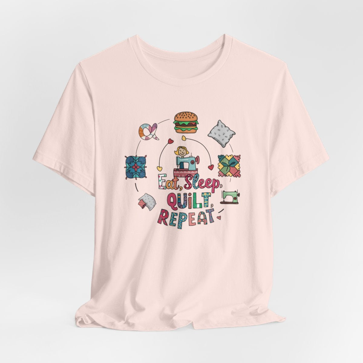 A Soft Pink funny quilting T-Shirt with the phrase Eat, Sleep, Quilt, Repeat  showing the cycle of a quilter's day with eating, sleeping, and quilting