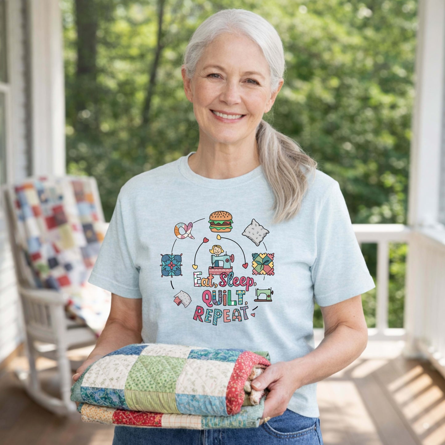 A Heather Ice Blue Short Sleeve T-Shirt with a cute quilting elements with "Eat, Sleep, Quilt, Repeat" text in playful style