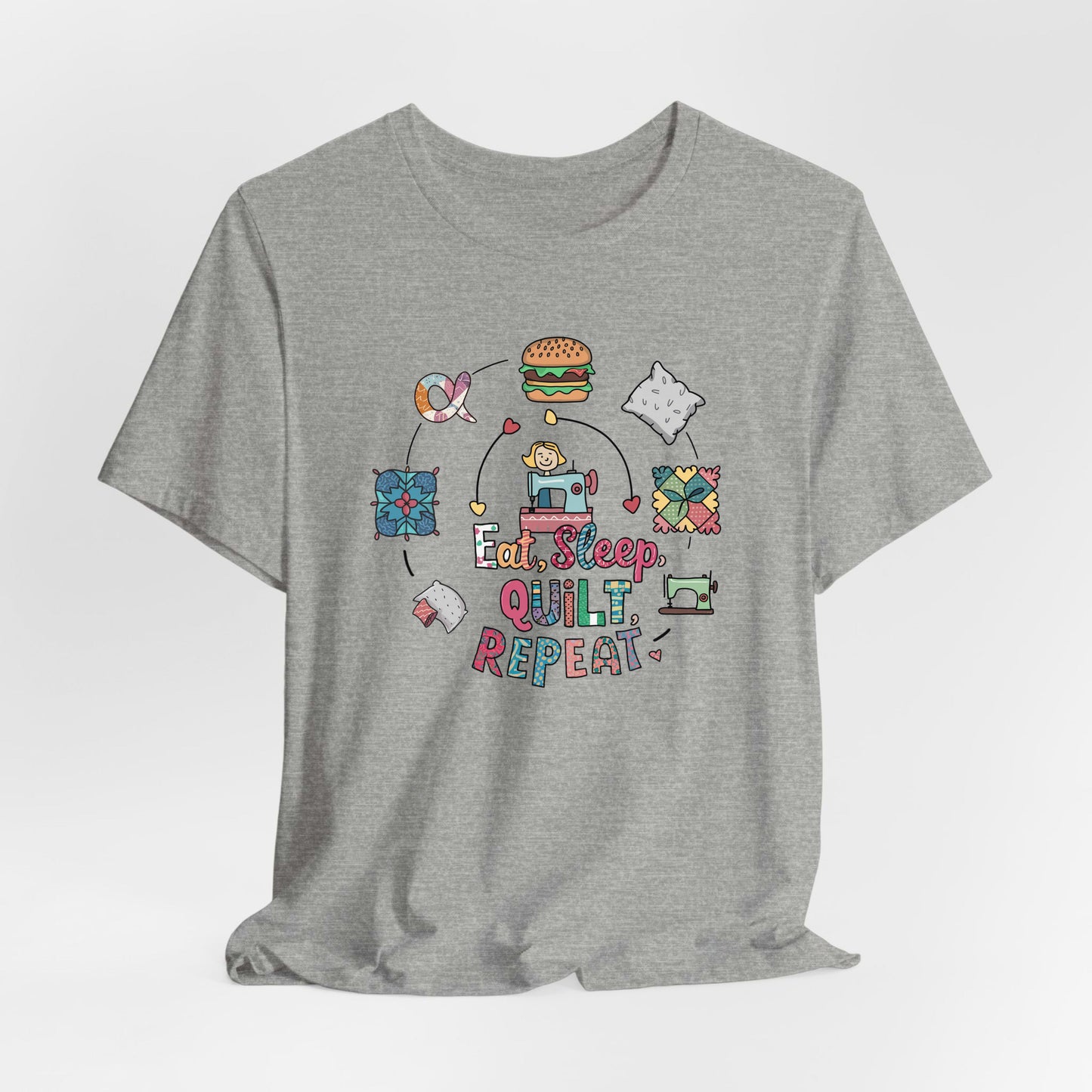 A Athletic Heather Short Sleeve T-Shirt with a cute quilting elements with "Eat, Sleep, Quilt, Repeat" text in playful style