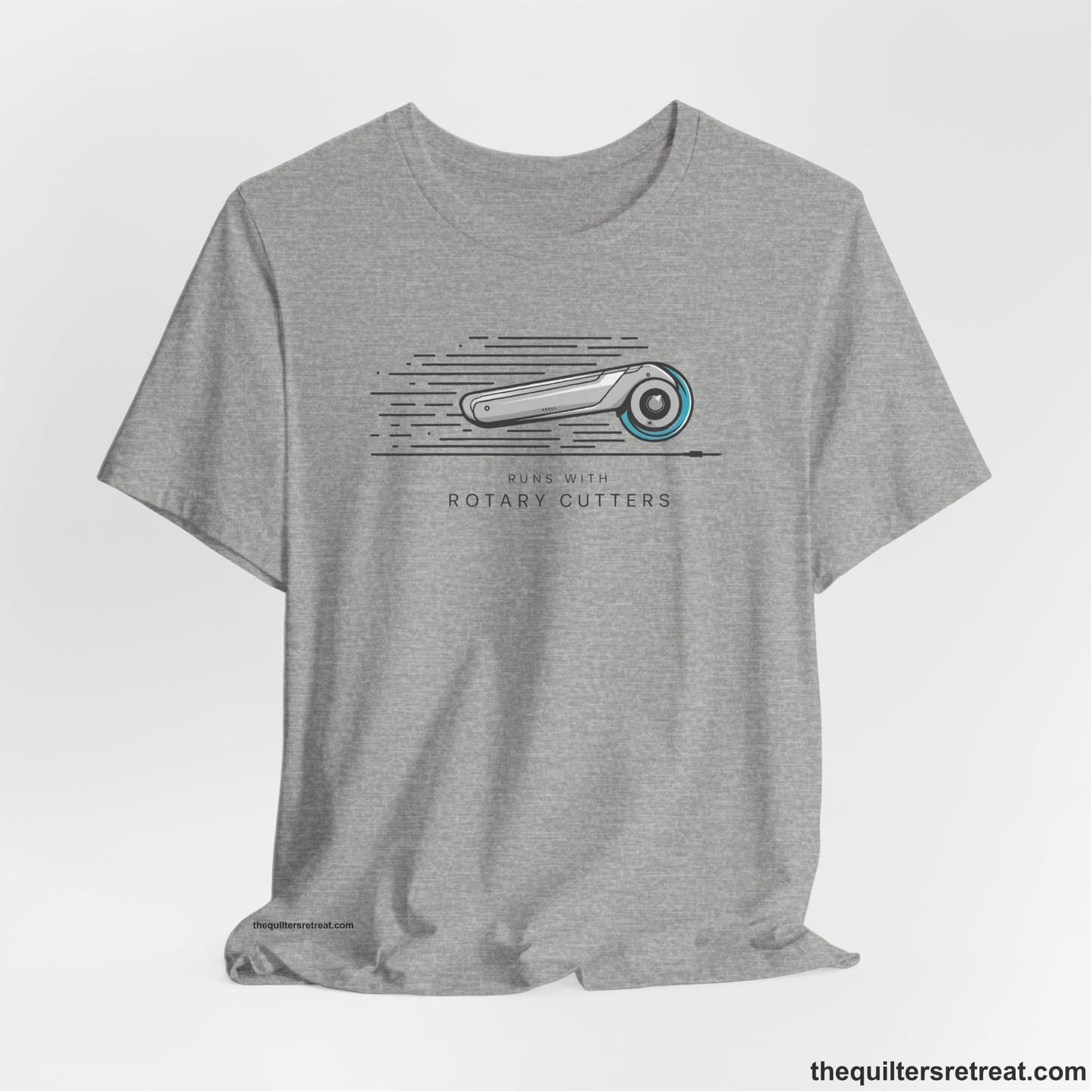 A Athletic Heather Short Sleeve T-Shirt with a rotary cutter illustration with dynamic lines and bold "Runs with Rotary Cutters" text
