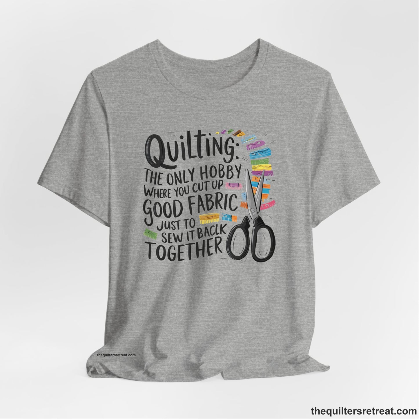 A Athletic Heather Short Sleeve T-Shirt with a quilting-themed text with colorful fabric pieces and scissors in a whimsical style