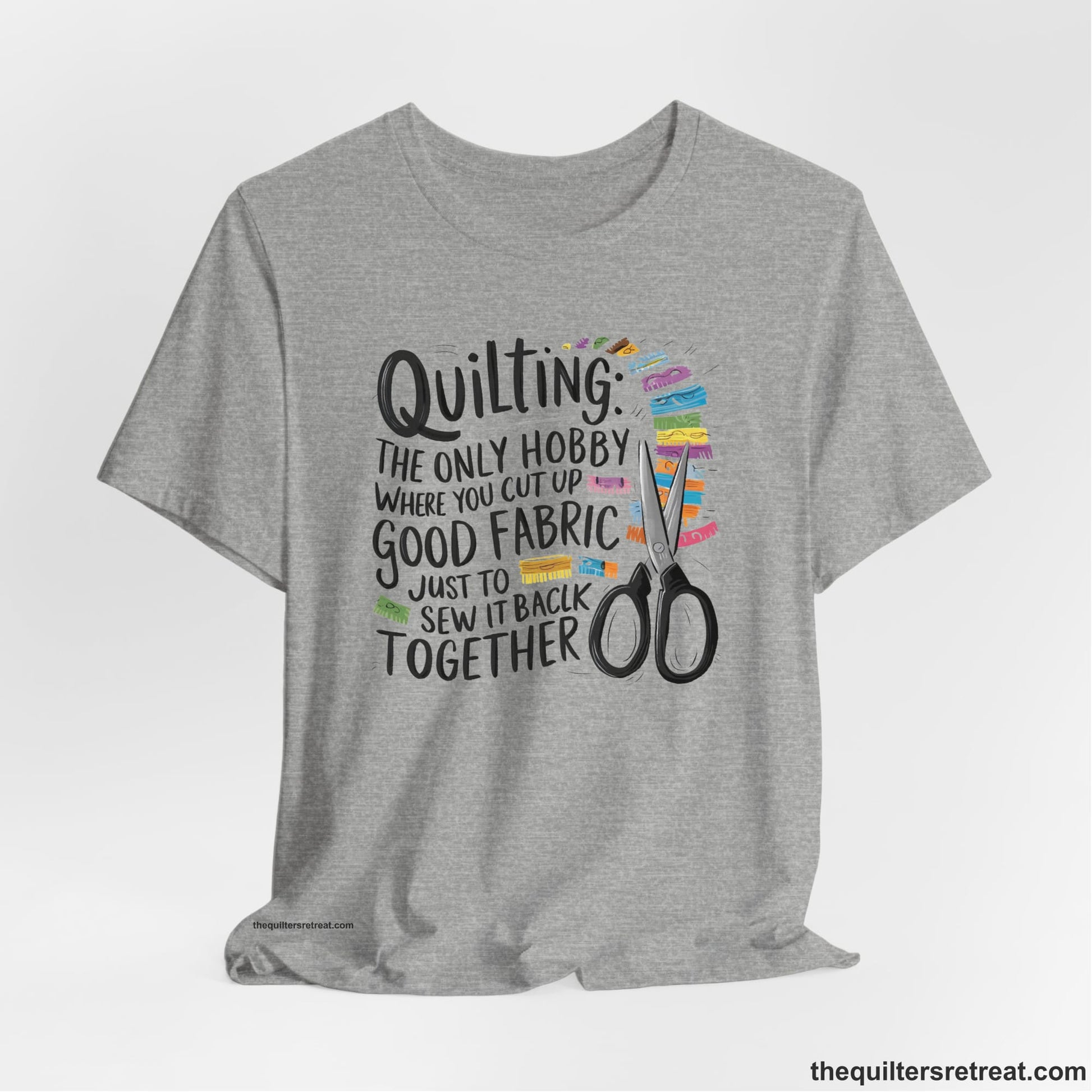 A Athletic Heather Short Sleeve T-Shirt with a quilting-themed text with colorful fabric pieces and scissors in a whimsical style