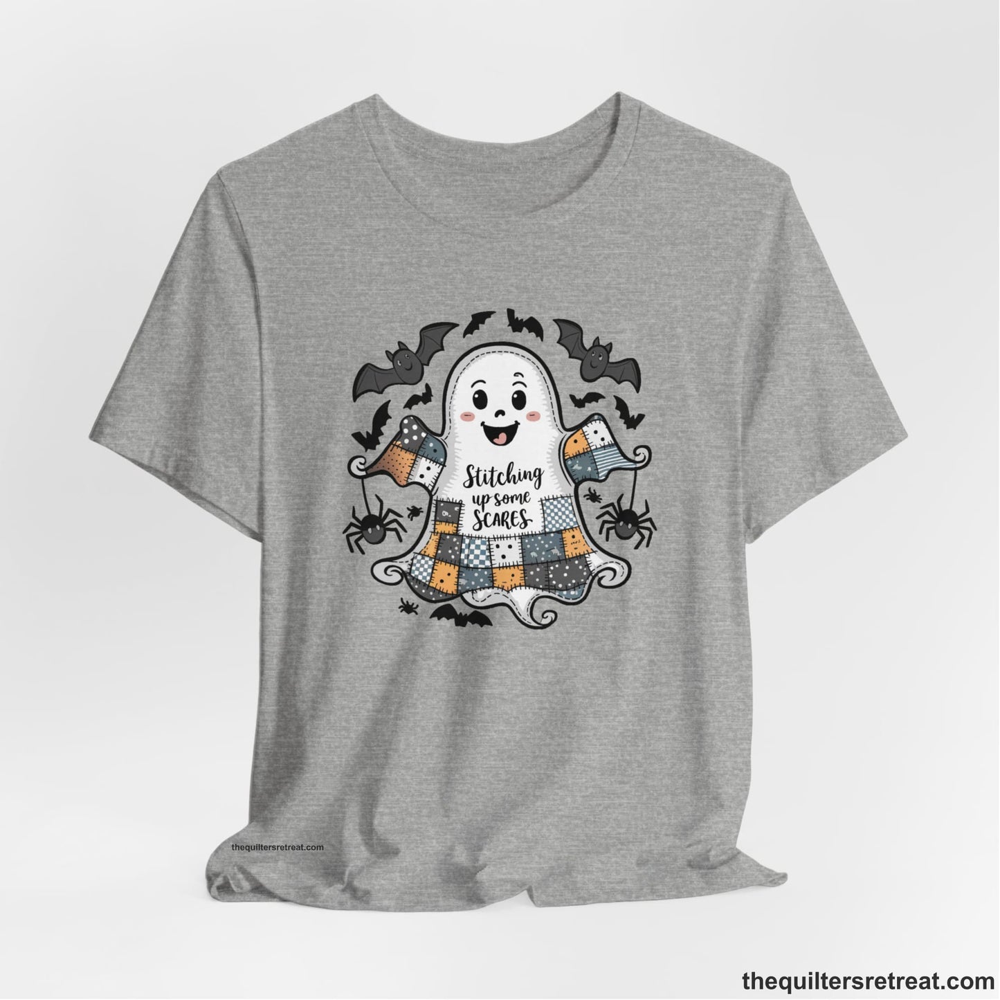 A Athletic Heather Short Sleeve T-Shirt with a cute patchwork ghost with "Stitching up some Scares" text and playful bats in a whimsical style
