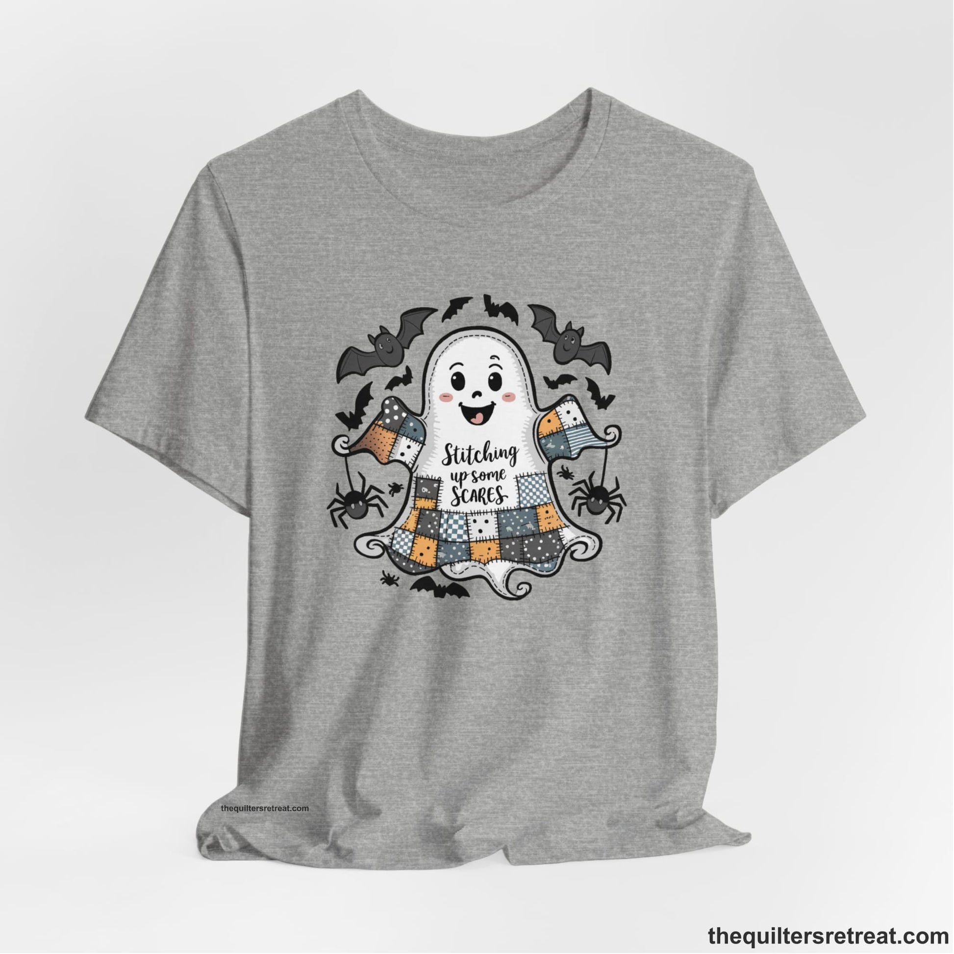 A Athletic Heather Short Sleeve T-Shirt with a cute patchwork ghost with "Stitching up some Scares" text and playful bats in a whimsical style
