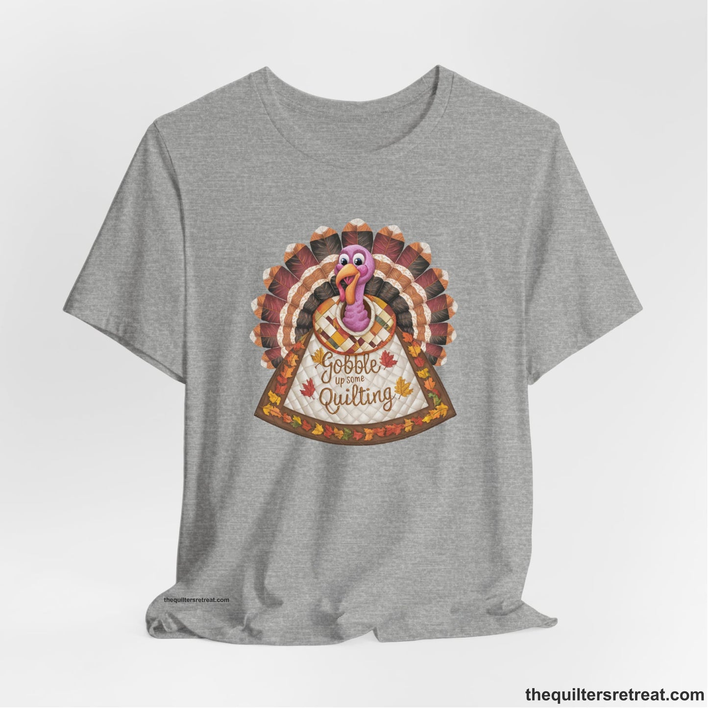 A Athletic Heather Short Sleeve T-Shirt with a colorful turkey with quilted feathers and "Gobble Up Some Quilting" text in a playful style