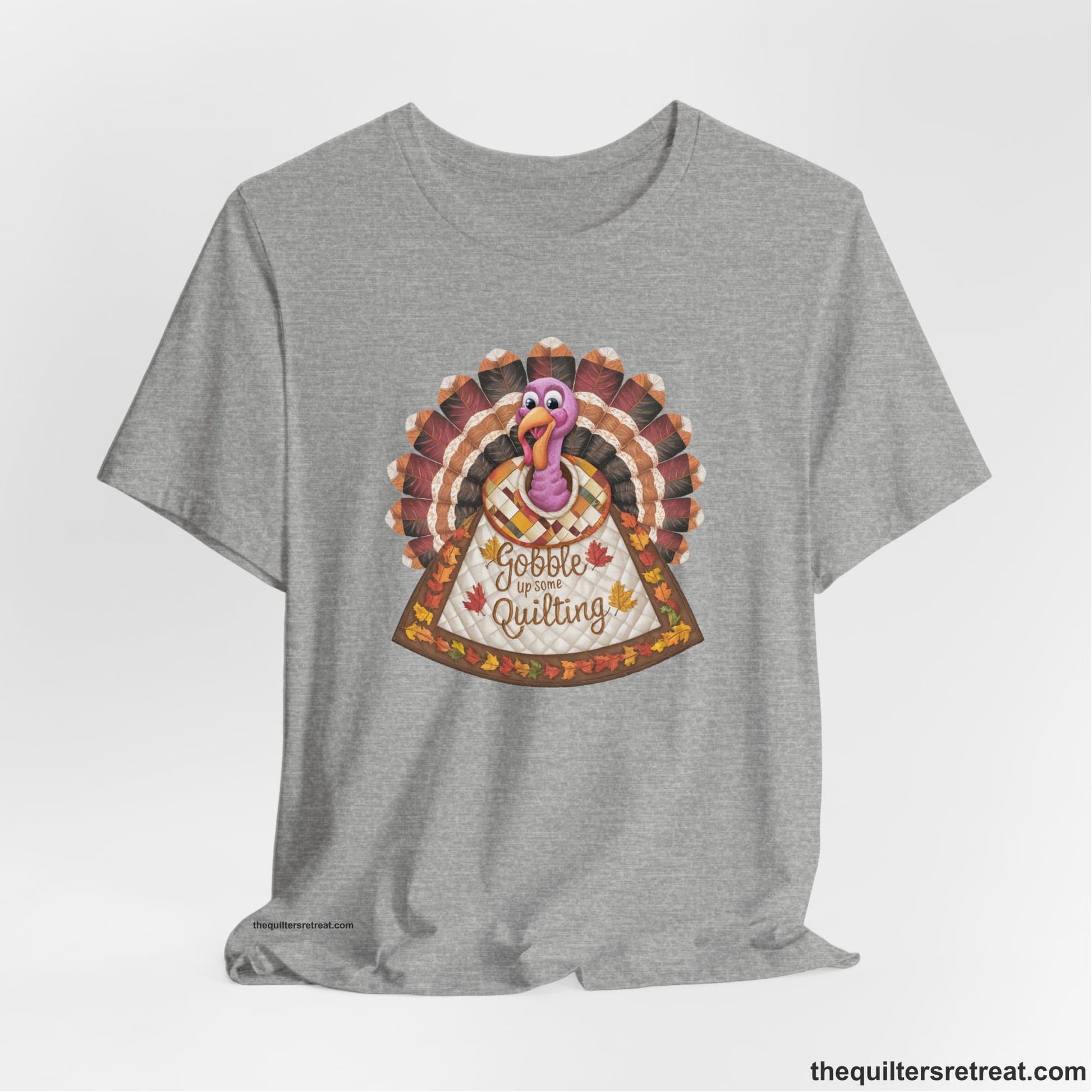 A Athletic Heather Short Sleeve T-Shirt with a colorful turkey with quilted feathers and "Gobble Up Some Quilting" text in a playful style
