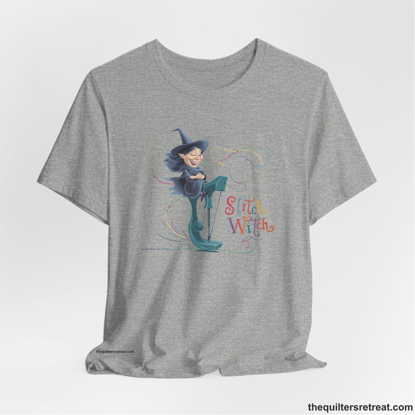 A Athletic Heather Short Sleeve T-Shirt with a witch on vintage sewing machine with "Stitch Witch" text in playful, colorful style