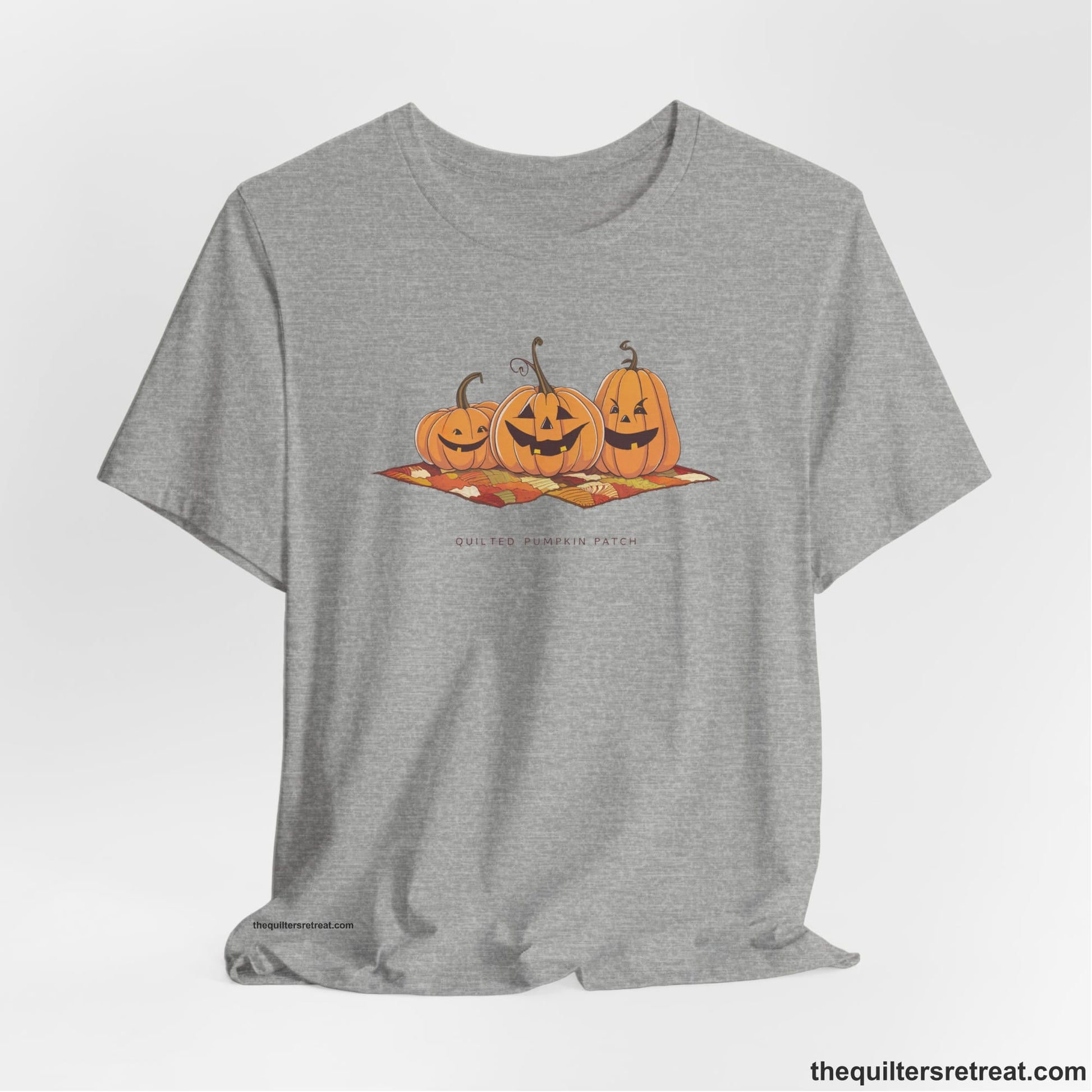 A Athletic Heather Short Sleeve T-Shirt with a playful jack-o'-lantern trio on a quilt with "Quilted Pumpkin Patch" text