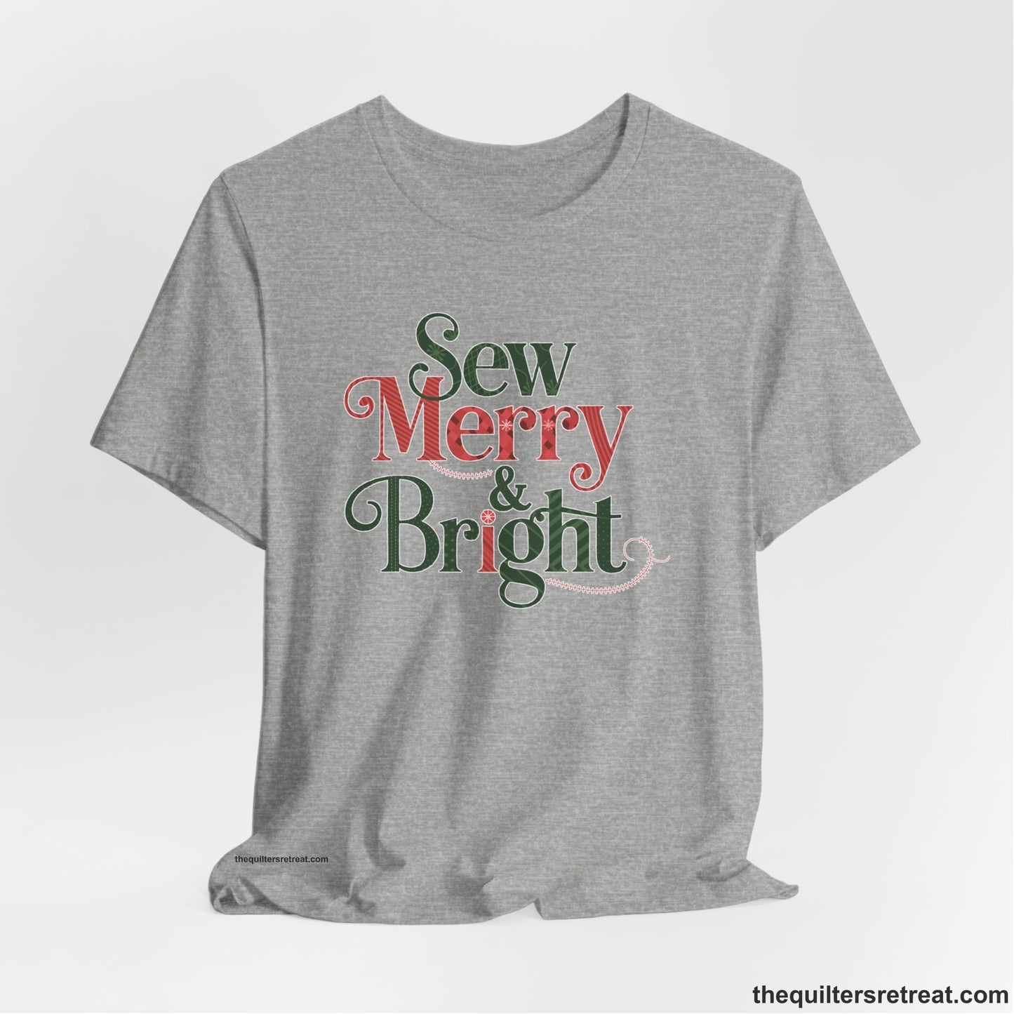 A Athletic Heather Short Sleeve T-Shirt with a festive "Sew Merry & Bright" text with decorative holiday patterns
