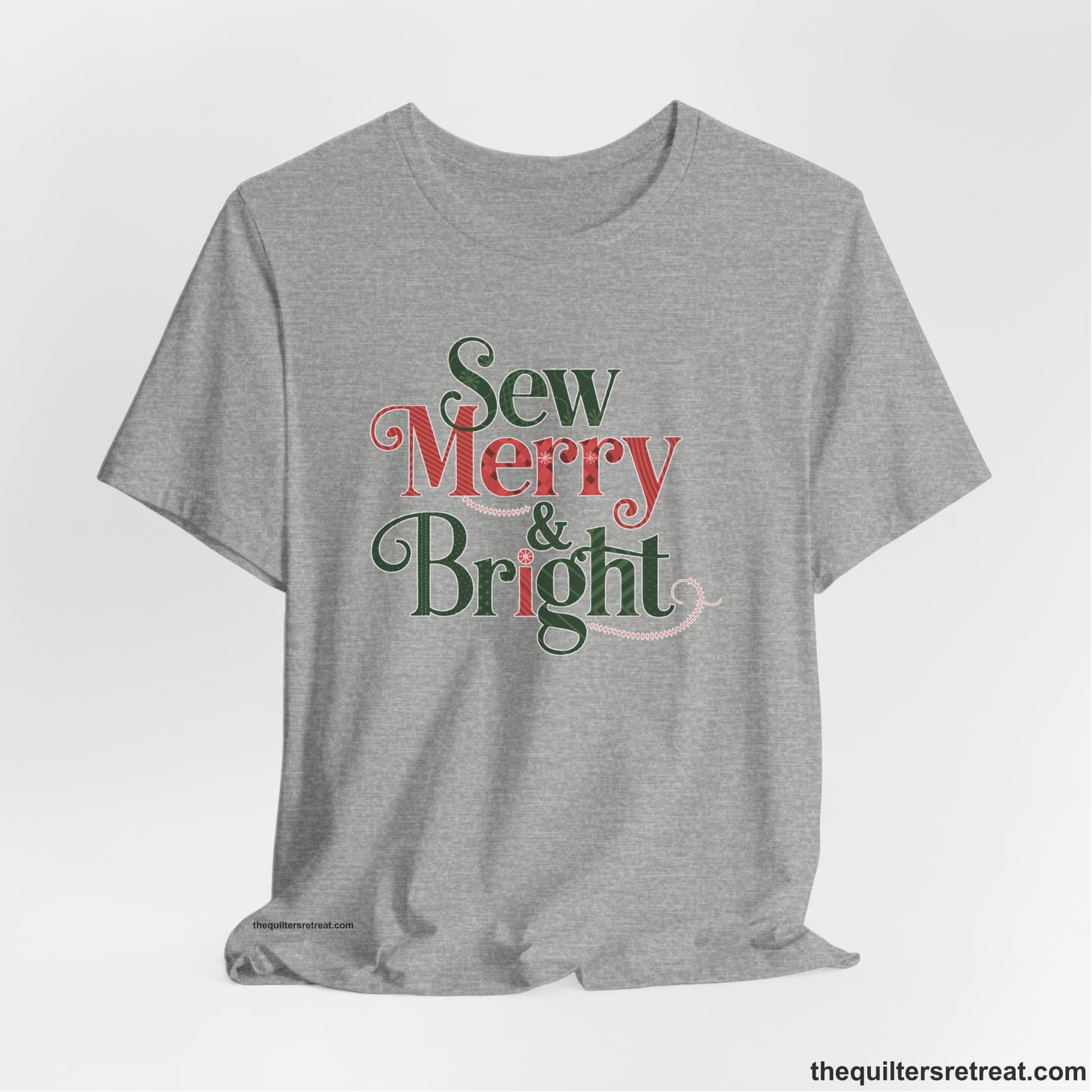 A Athletic Heather Short Sleeve T-Shirt with a festive "Sew Merry & Bright" text with decorative holiday patterns