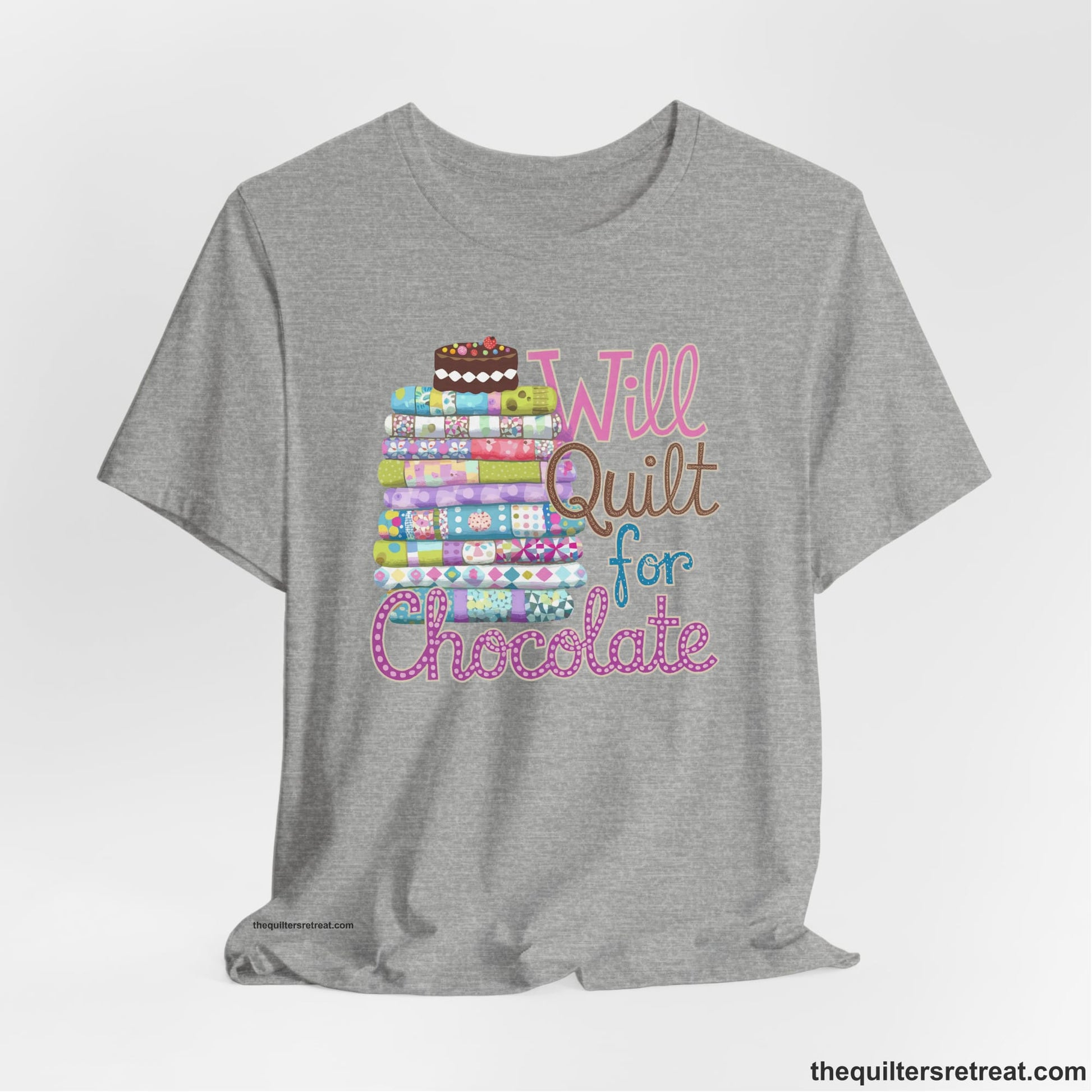 A Athletic Heather Short Sleeve T-Shirt with a stack of colorful quilts topped with cake, whimsical "Will Quilt for Chocolate" text