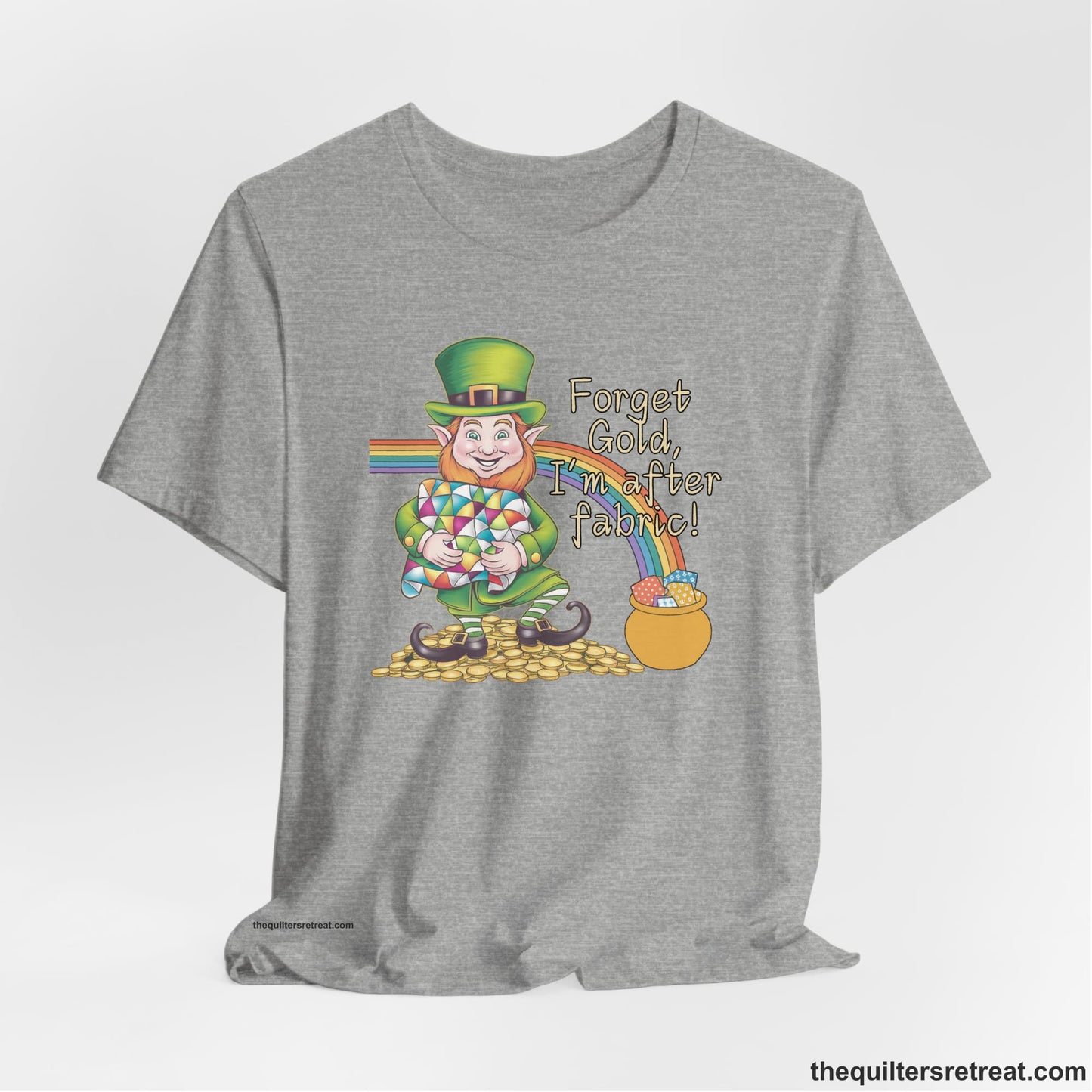 A Athletic Heather Short Sleeve T-Shirt with a leprechaun with colorful quilt and rainbow, whimsical "Forget Gold, I'm after fabric!" text