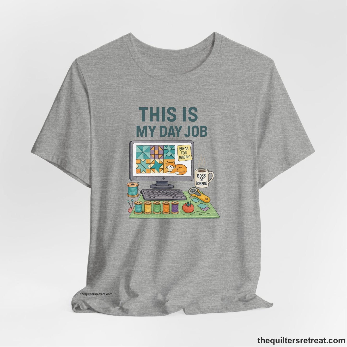 A Athletic Heather Short Sleeve T-Shirt with a computer quilt design, cat illustration, "THIS IS MY DAY JOB" text with sewing tools, playful style