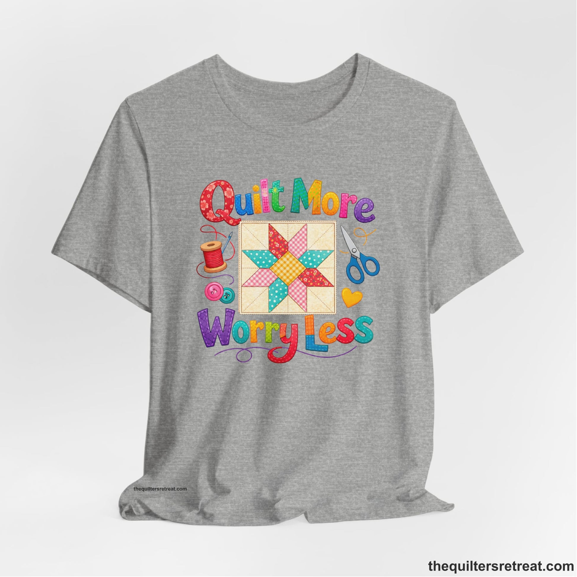 A Athletic Heather Short Sleeve T-Shirt with a Colorful patchwork star and sewing tools, cheerful "Quilt More Worry Less" text.