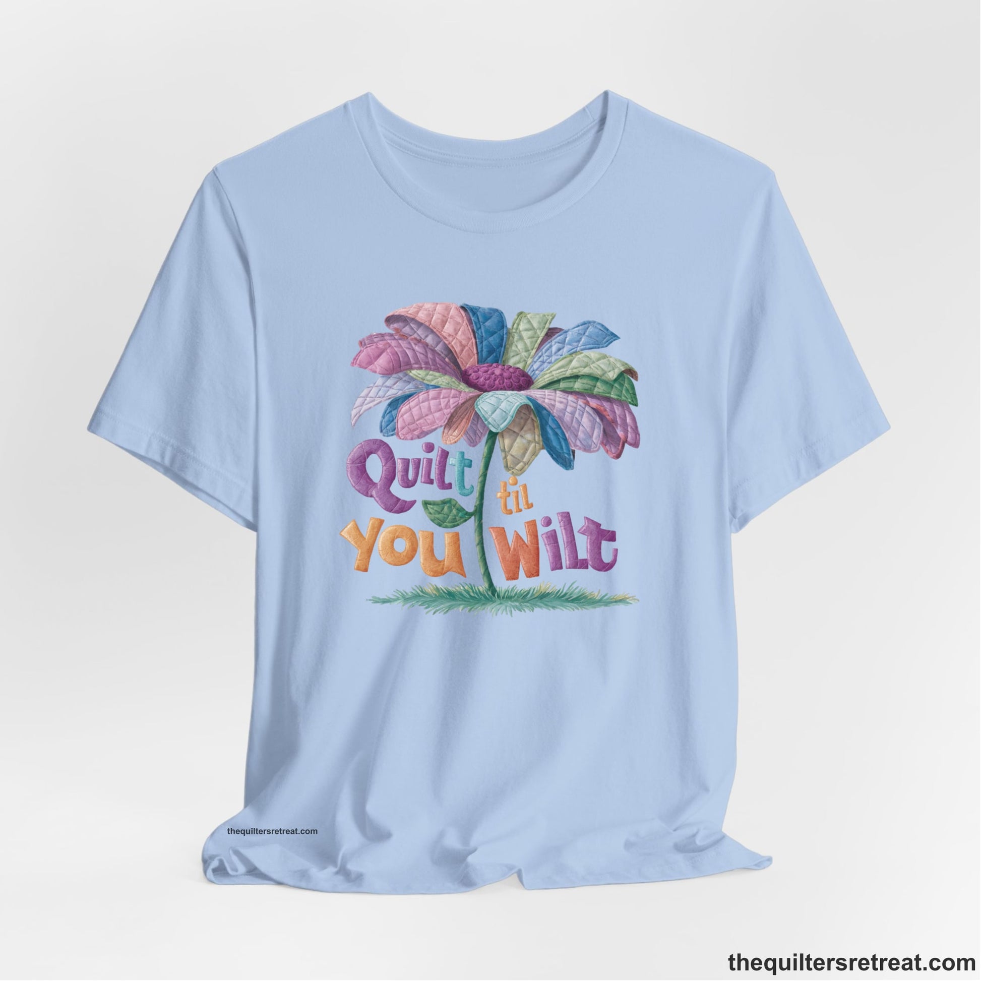 A Baby Blue Short Sleeve T-Shirt with a whimsical quilted flower with bold "Quilt til You Wilt" text