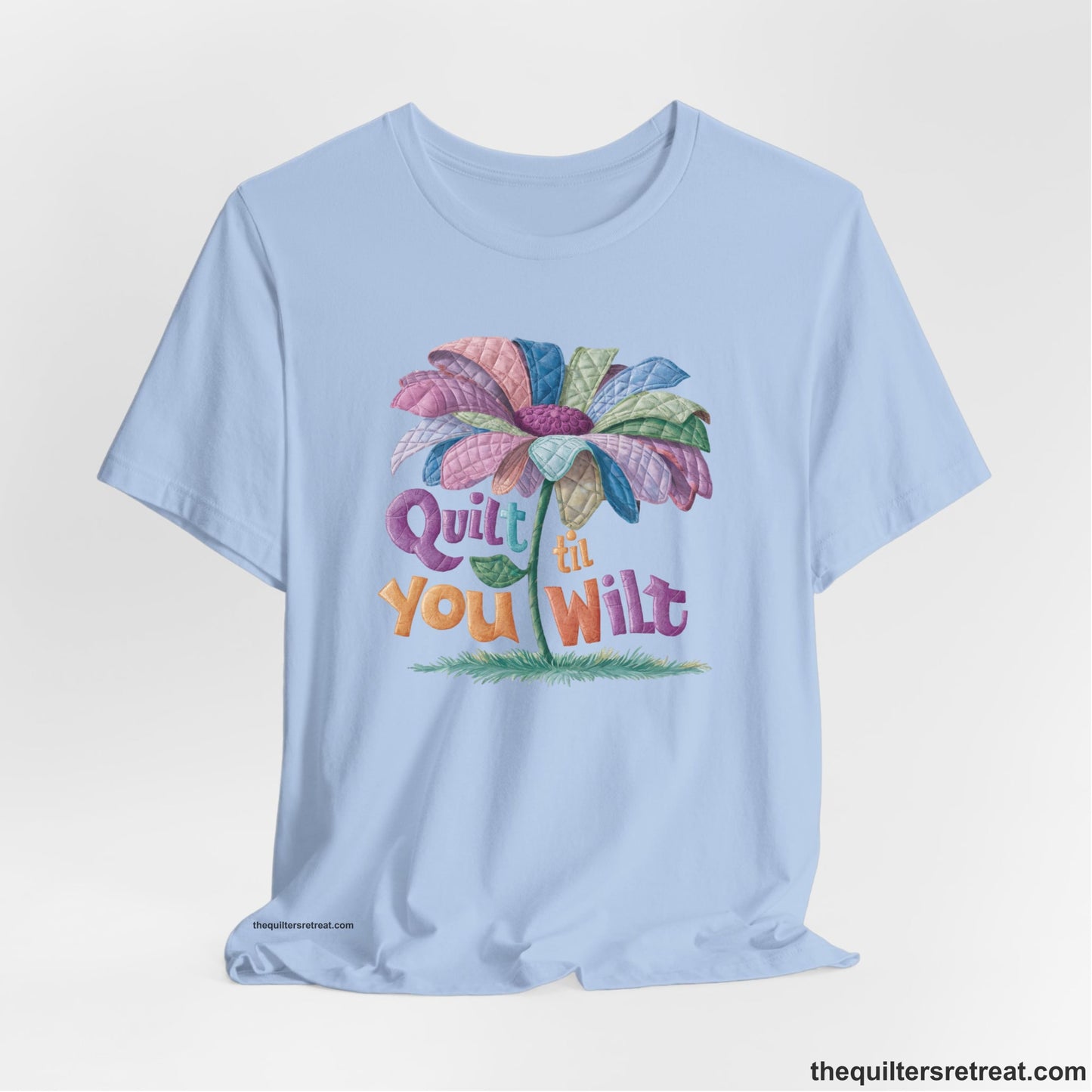 A Baby Blue Short Sleeve T-Shirt with a whimsical quilted flower with bold "Quilt til You Wilt" text