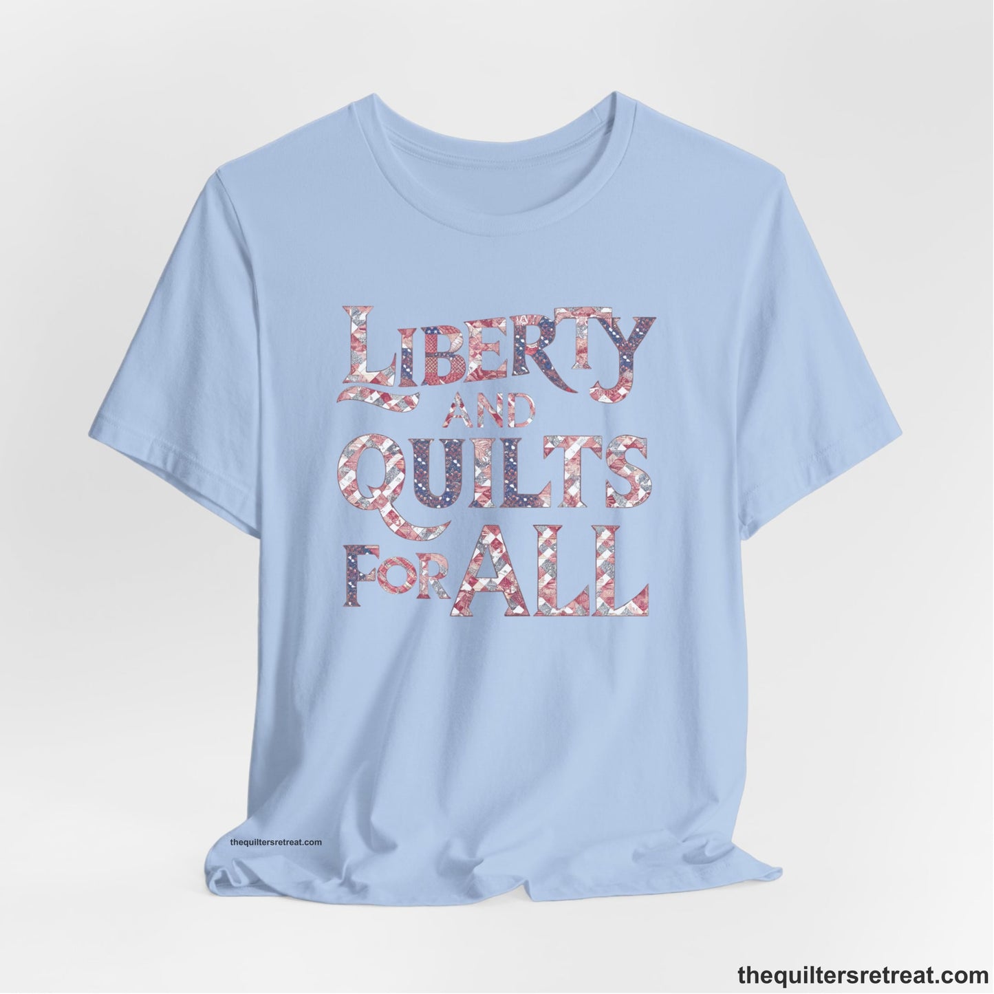 A Baby Blue Short Sleeve T-Shirt with a Liberty and Quilts for All" text with patchwork quilt pattern in a vintage style