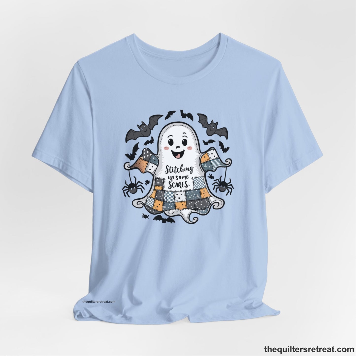 A Baby Blue Short Sleeve T-Shirt with a cute patchwork ghost with "Stitching up some Scares" text and playful bats in a whimsical style