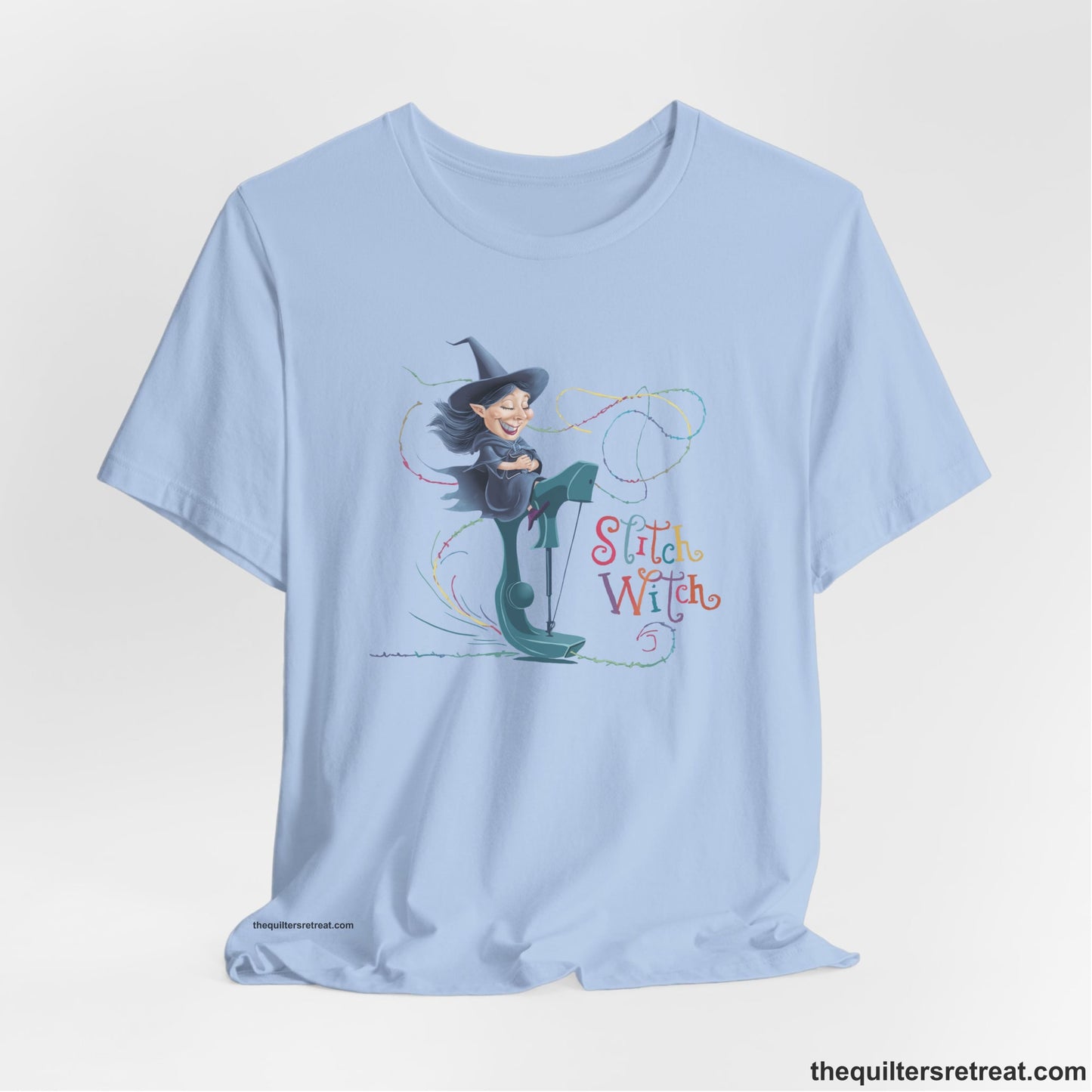 A Baby Blue Short Sleeve T-Shirt with a witch on vintage sewing machine with "Stitch Witch" text in playful, colorful style