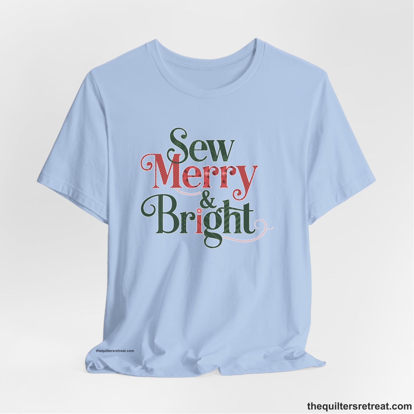 A Baby Blue Short Sleeve T-Shirt with a festive "Sew Merry & Bright" text with decorative holiday patterns